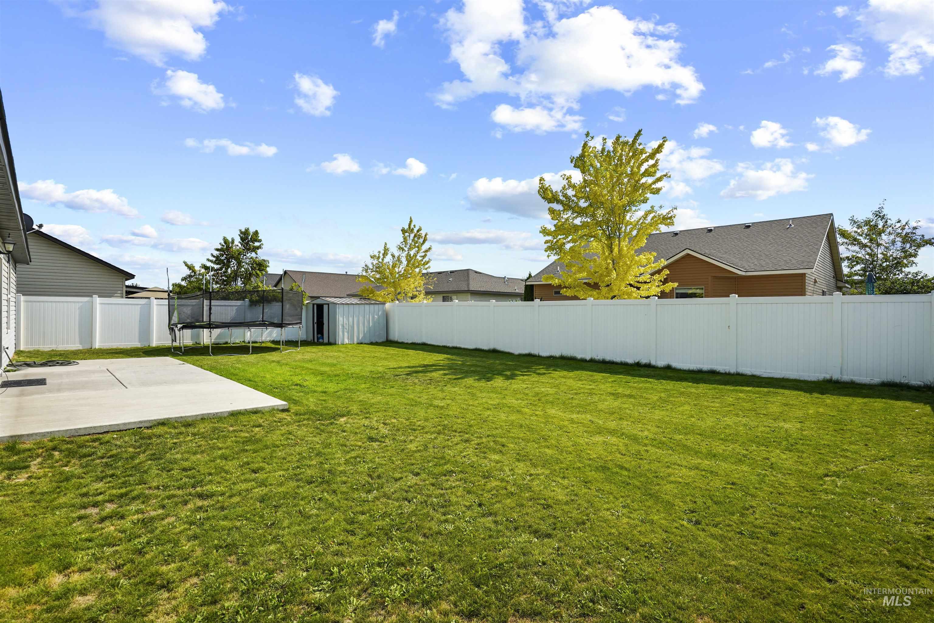 Fenced backyard featuring a trampoline, a patio, and a residential view