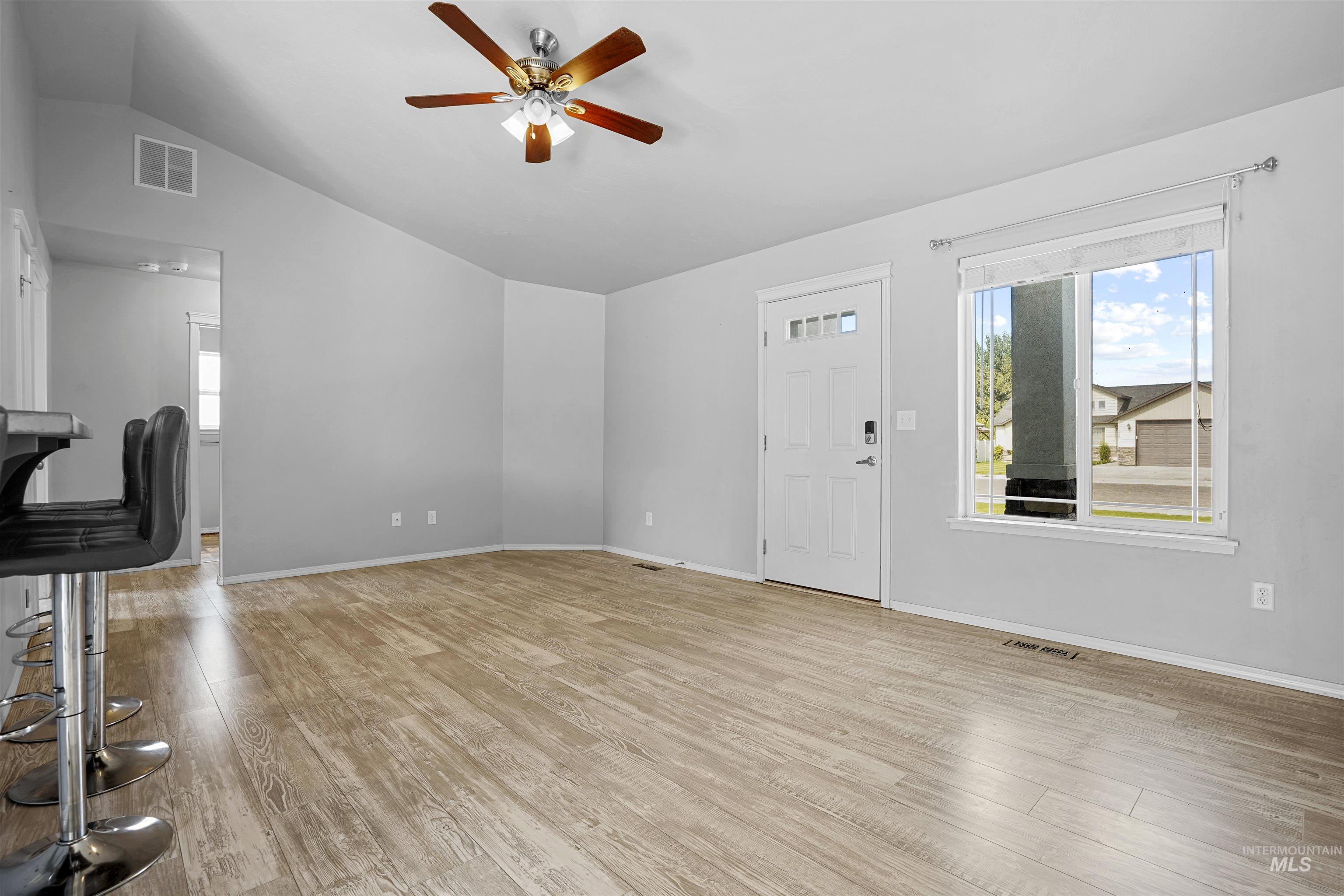 Unfurnished living room with vaulted ceiling, light wood-style floors, and a ceiling fan