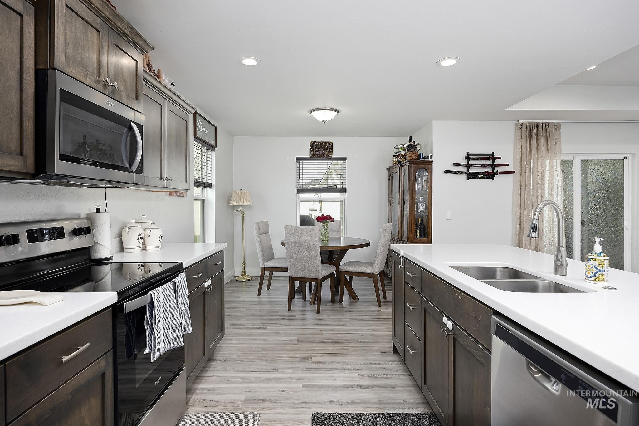 Kitchen with stainless steel appliances, dark brown cabinets, recessed lighting, and light wood finished floors