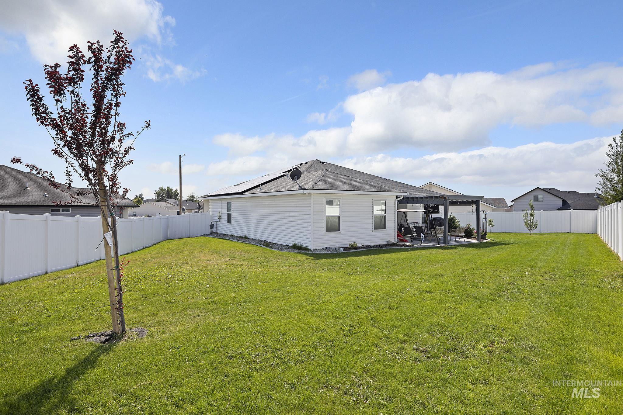 Rear view of property featuring a fenced backyard, a patio area, a pergola, and roof mounted solar panels