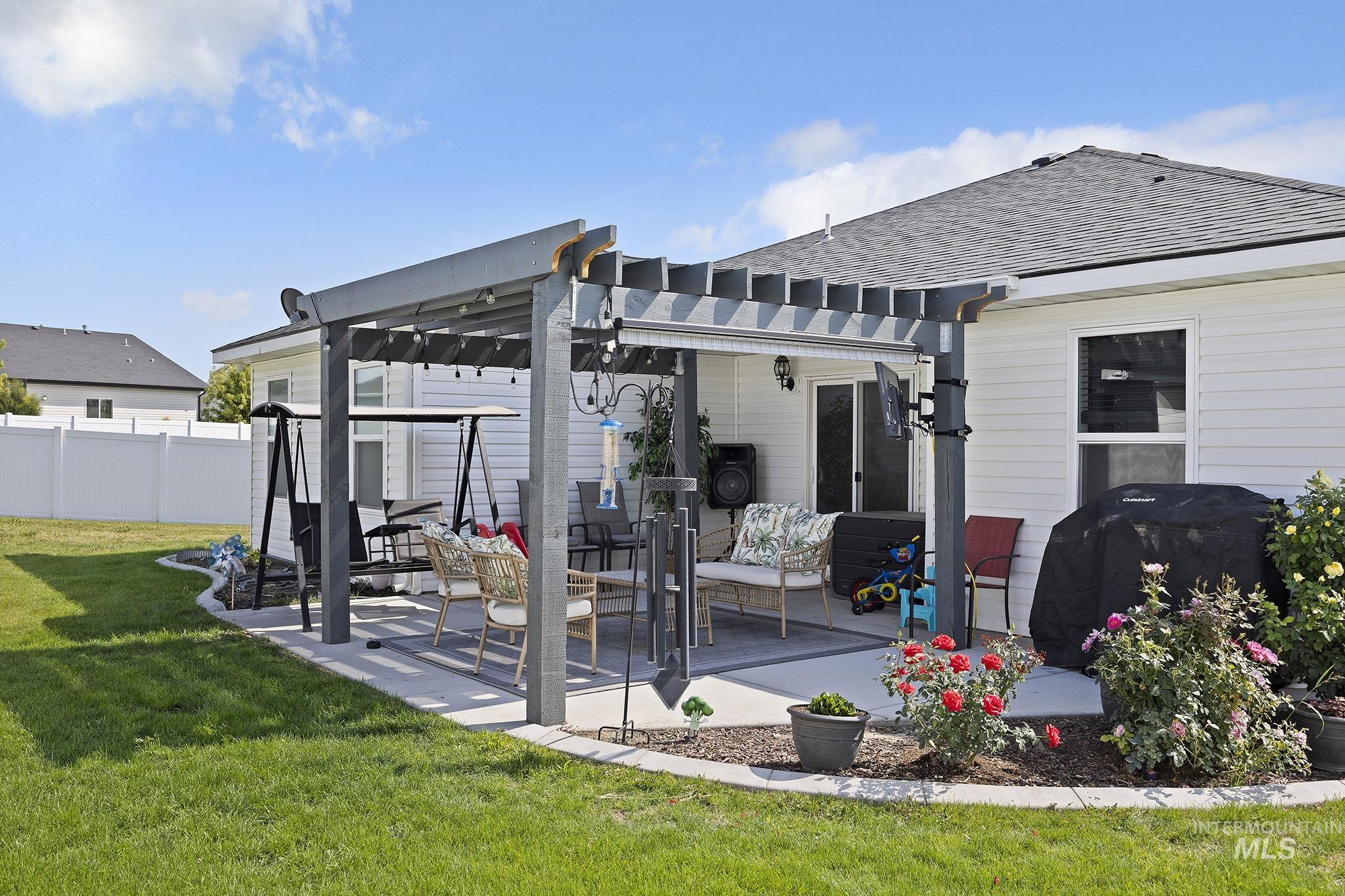 Rear view of house featuring a pergola, a patio area, and a shingled roof