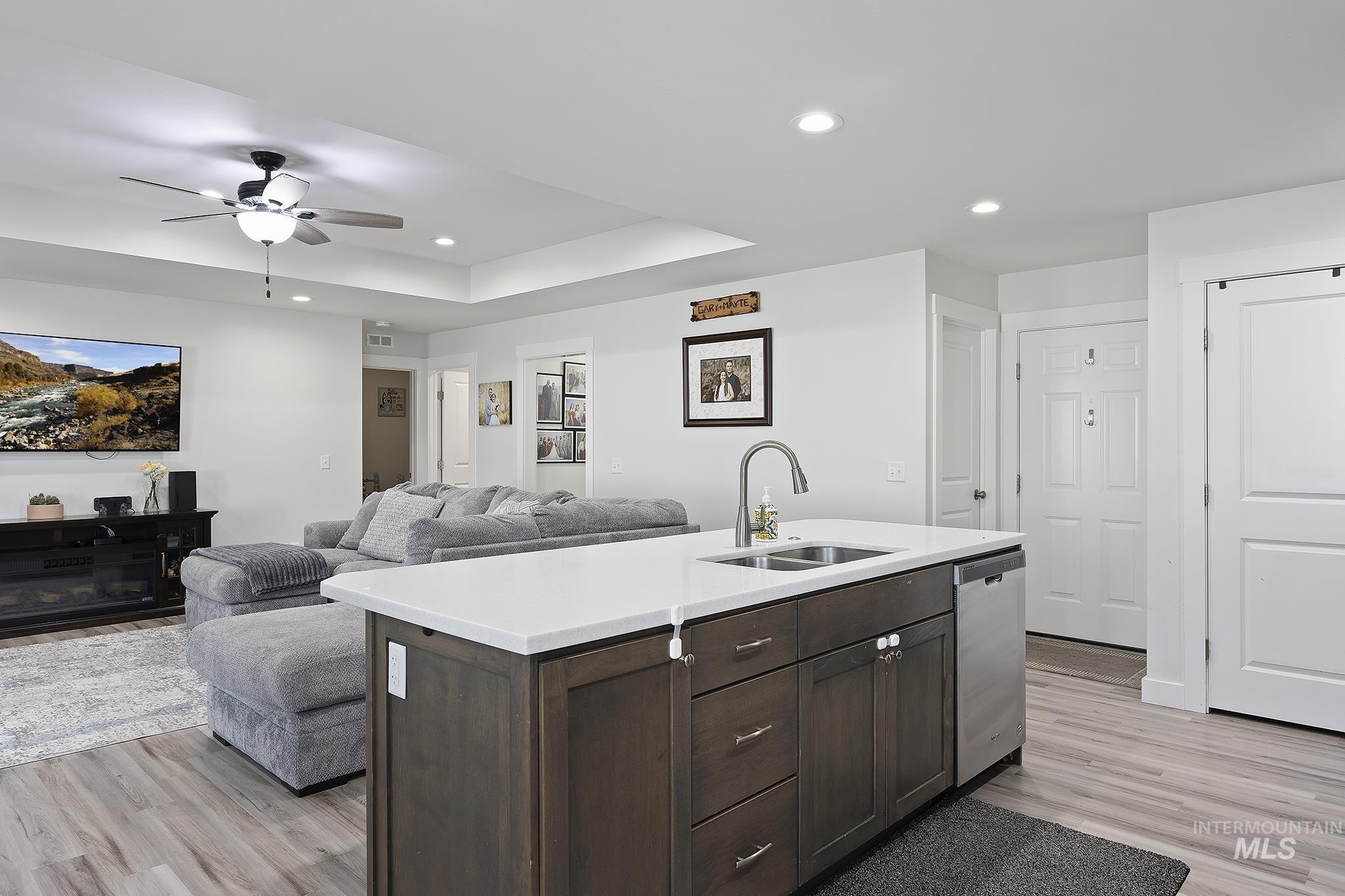 Kitchen with recessed lighting, dark brown cabinets, open floor plan, a kitchen island with sink, and light wood-type flooring