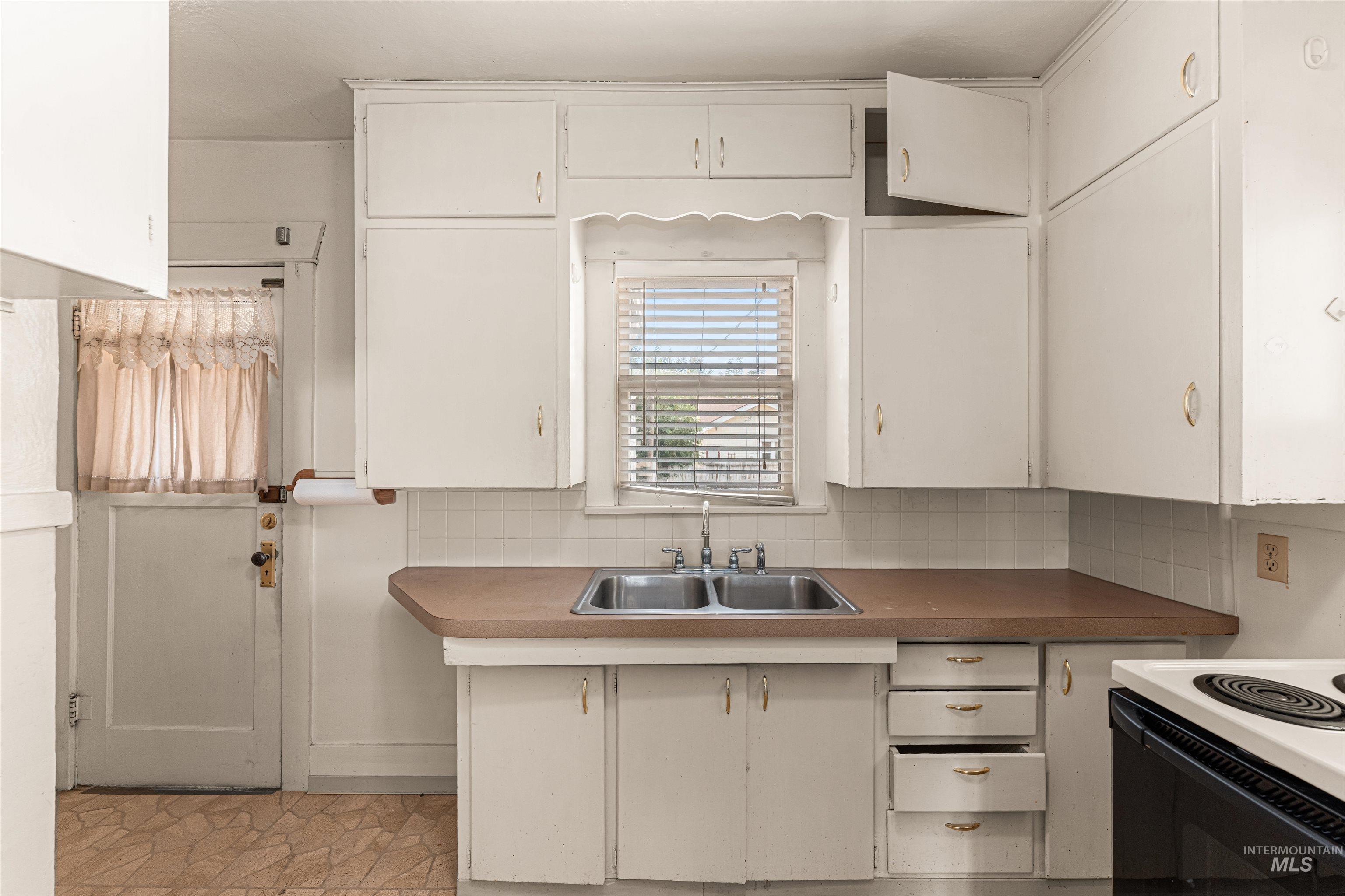 Kitchen featuring decorative backsplash, white range with electric stovetop, and white cabinets