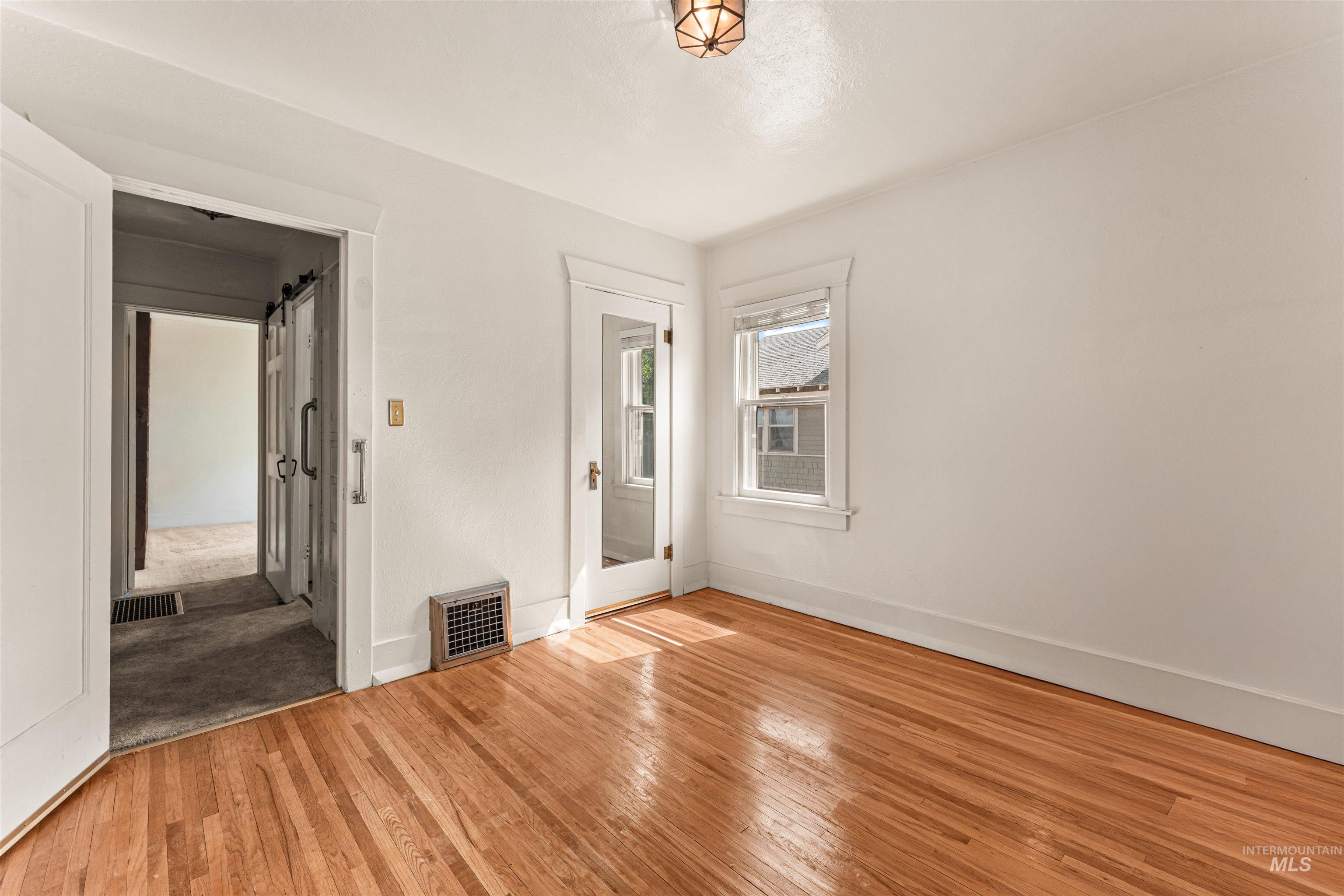 Unfurnished bedroom featuring wood-type flooring and a barn door