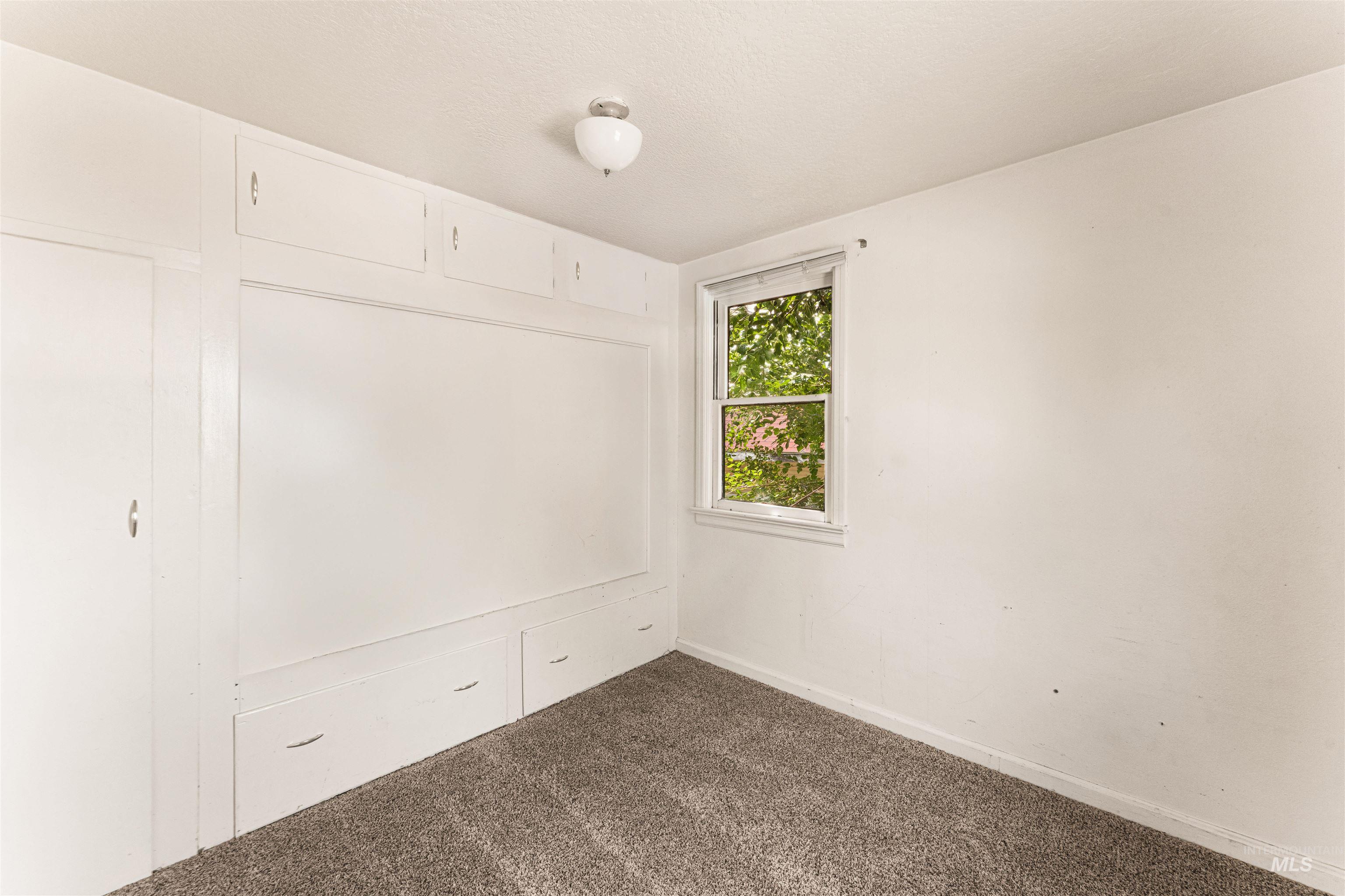 Unfurnished bedroom featuring dark carpet and baseboards