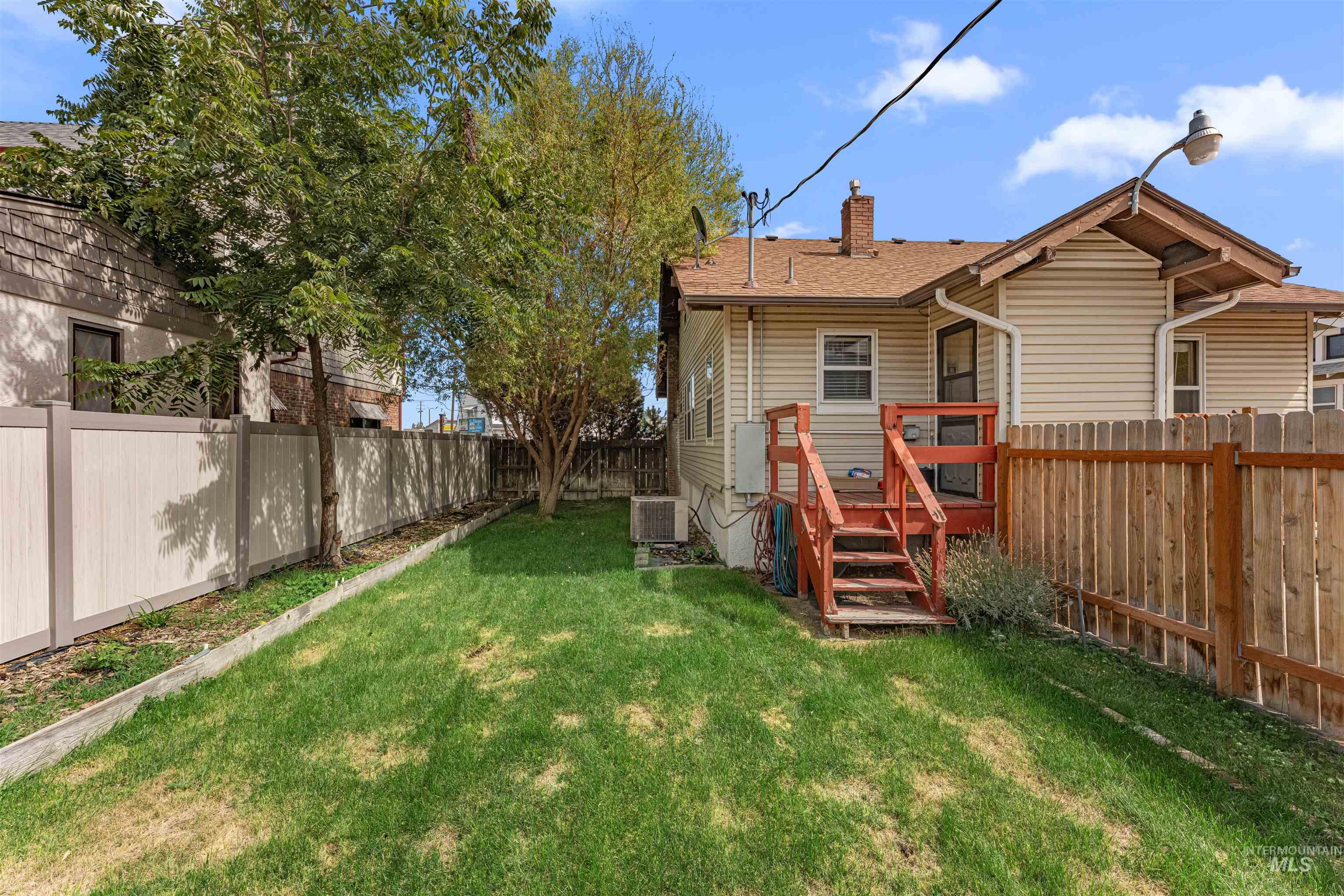 Rear view of house featuring a fenced backyard, a chimney, and a deck