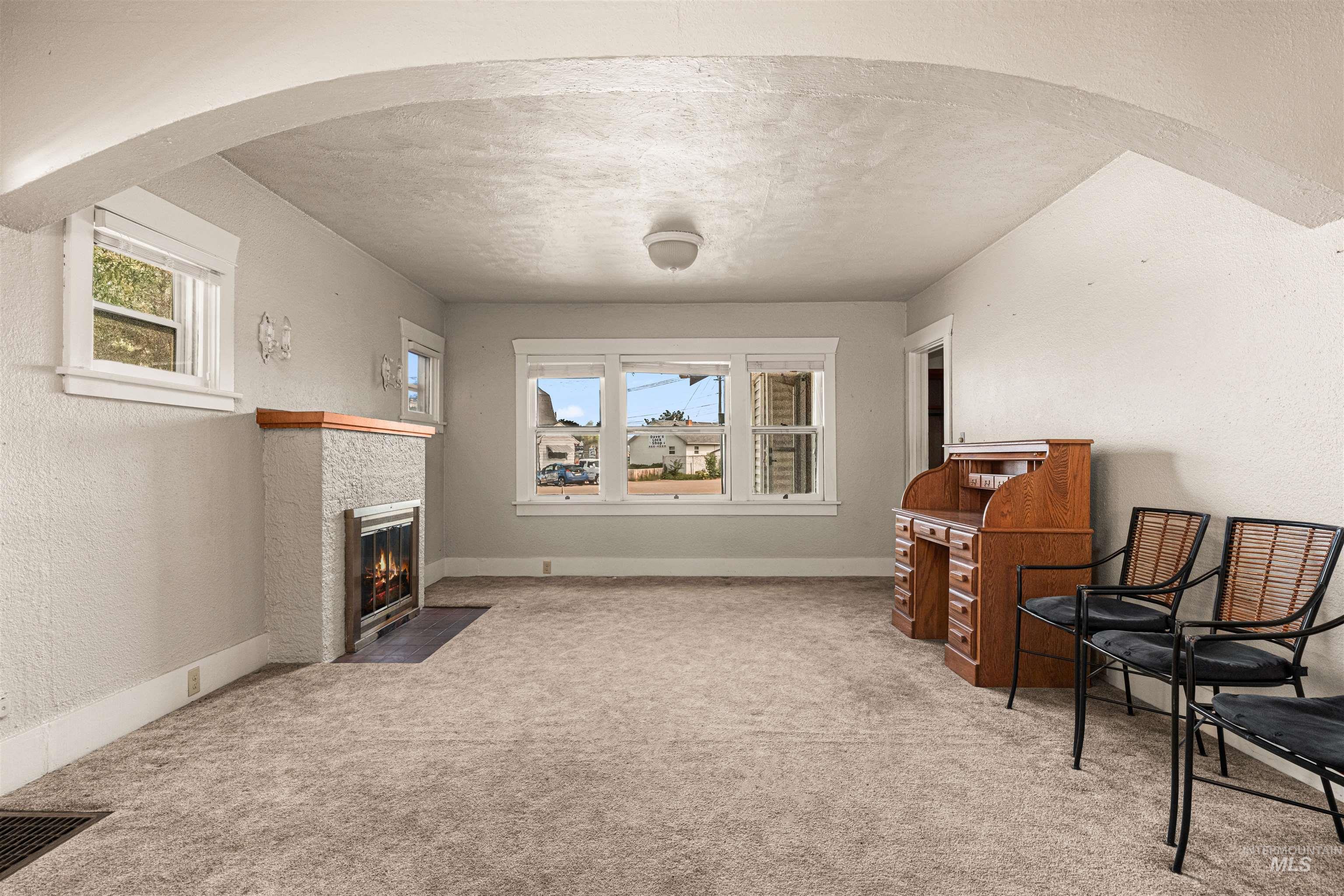 Sitting room with a textured wall, plenty of natural light, arched walkways, light carpet, and a textured ceiling