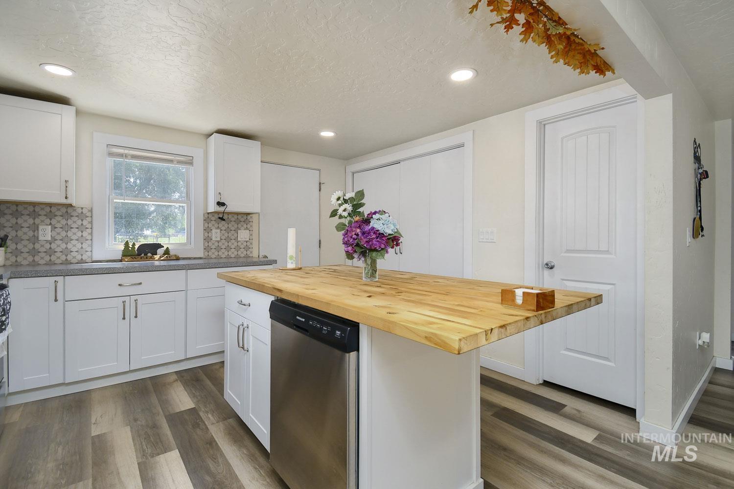 Kitchen featuring white cabinets, wood counters, dishwasher, a textured ceiling, and dark wood-style floors