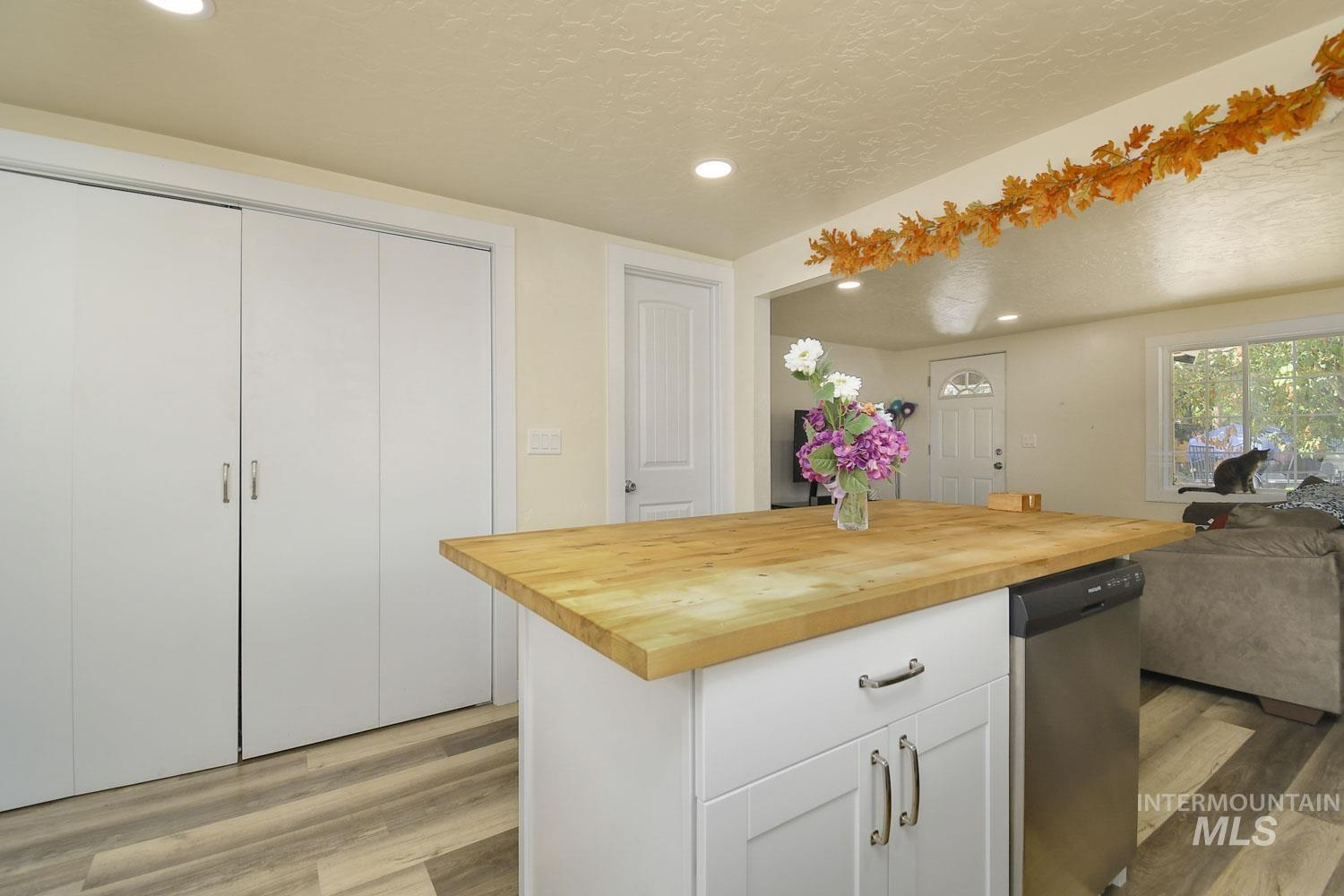 Kitchen with white cabinets, butcher block countertops, light wood-style flooring, a textured ceiling, and recessed lighting