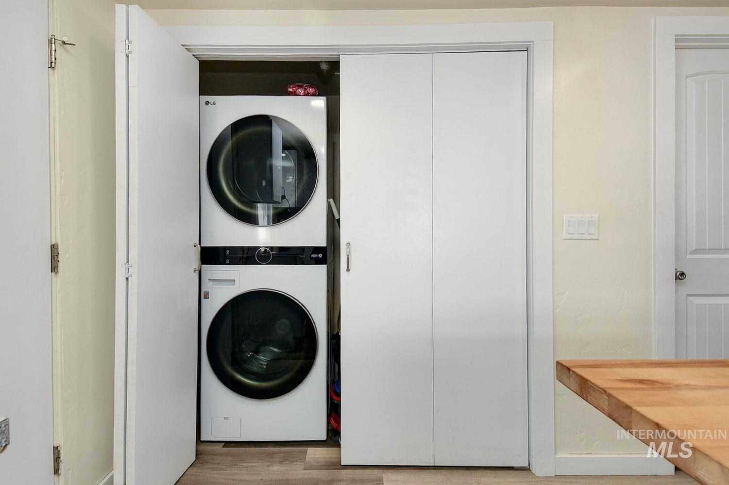 Washroom featuring stacked washer / dryer and light wood finished floors