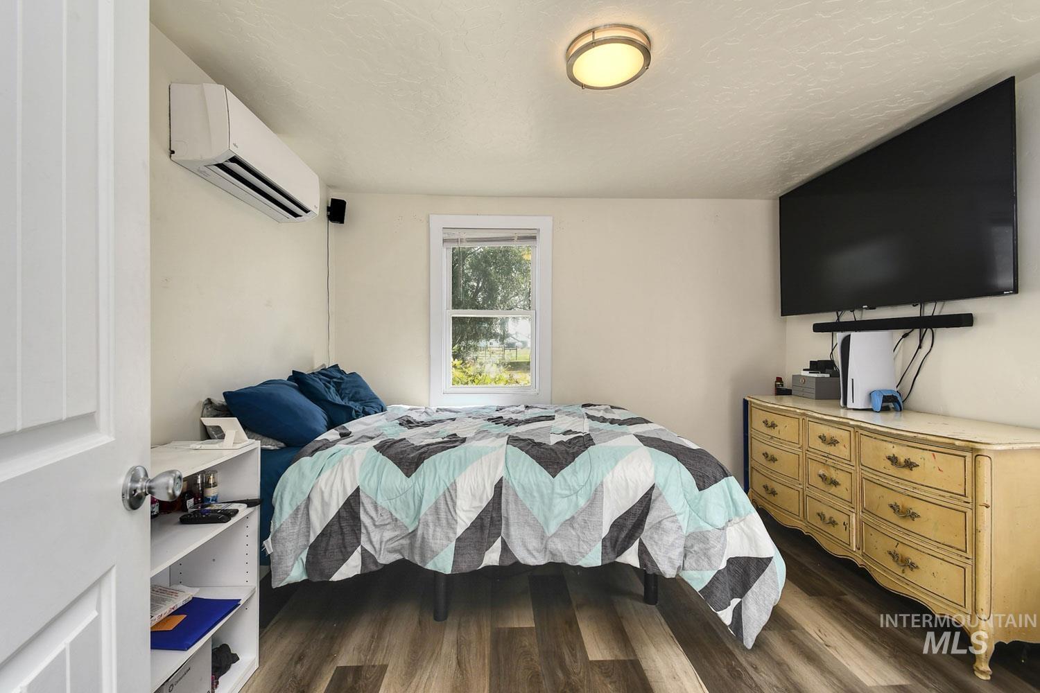 Bedroom featuring dark wood-style flooring, a textured ceiling, and a wall unit AC