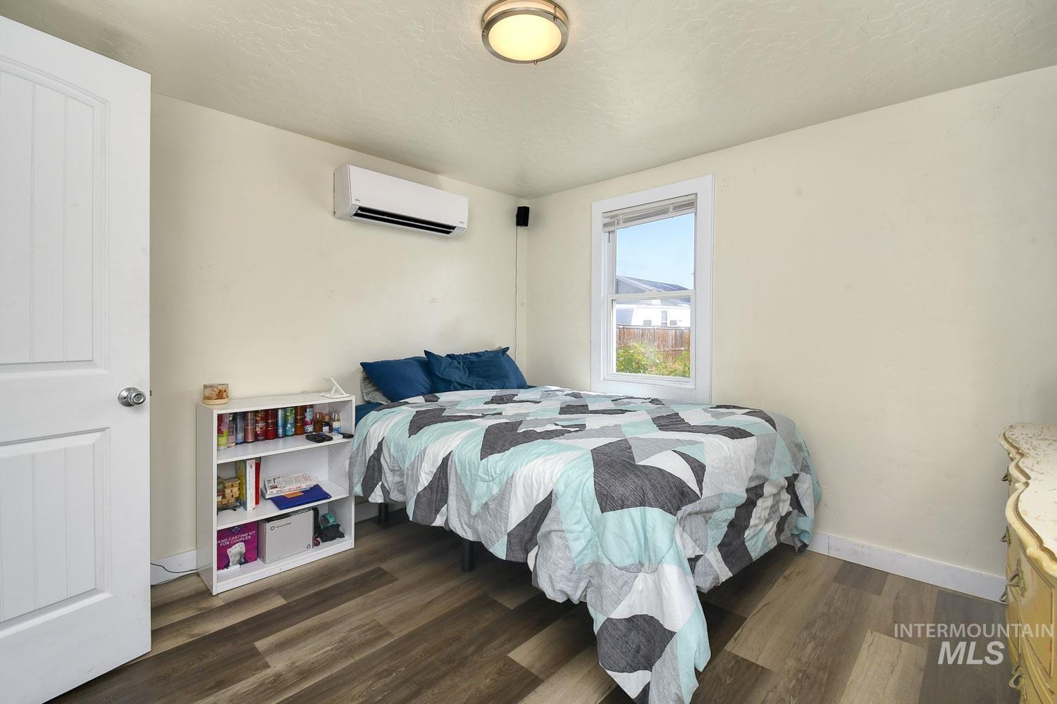 Bedroom with dark wood-style flooring, a textured ceiling, and a wall mounted air conditioner