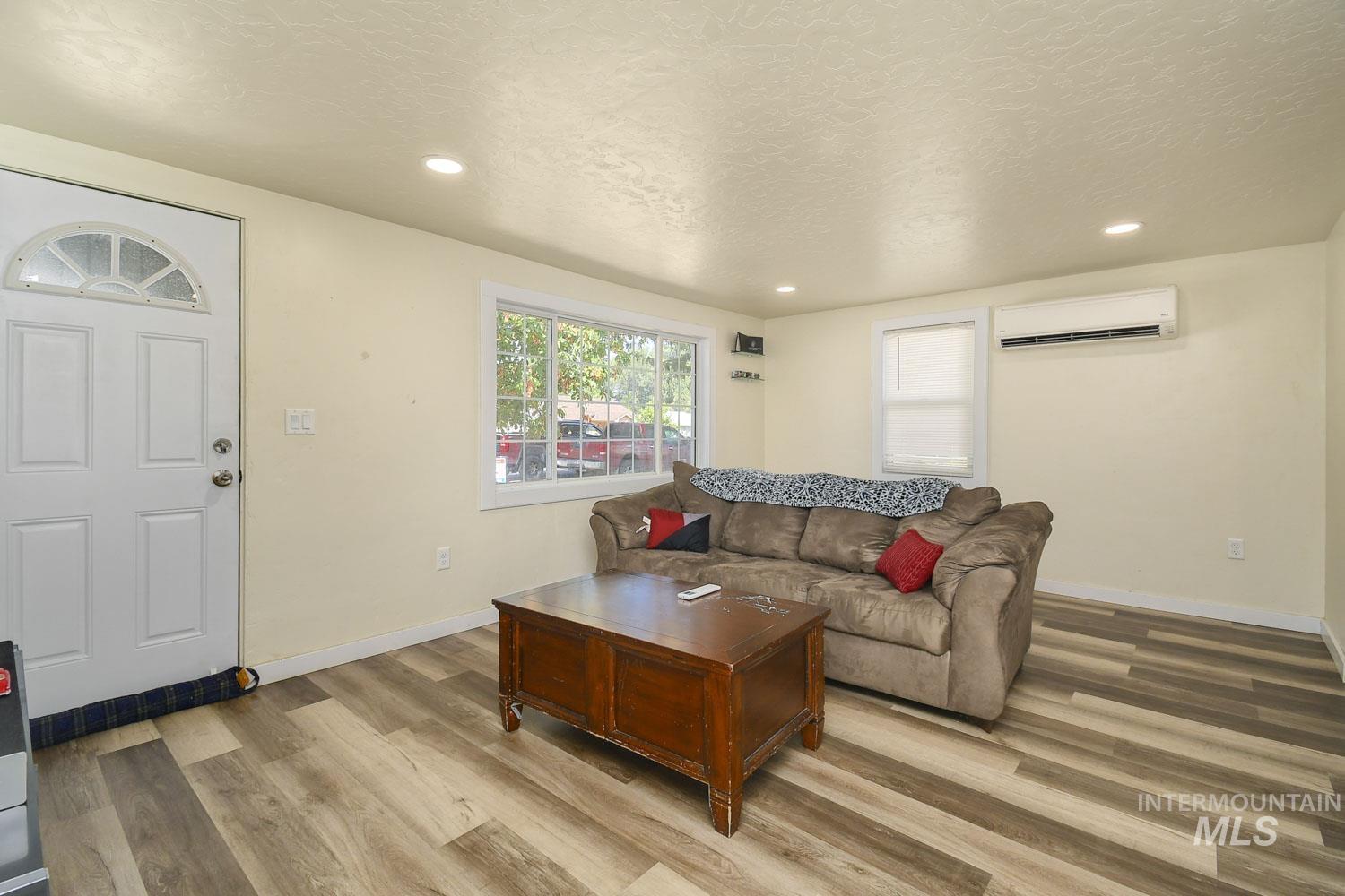 Living area featuring light wood-style floors, recessed lighting, a textured ceiling, and a wall mounted air conditioner