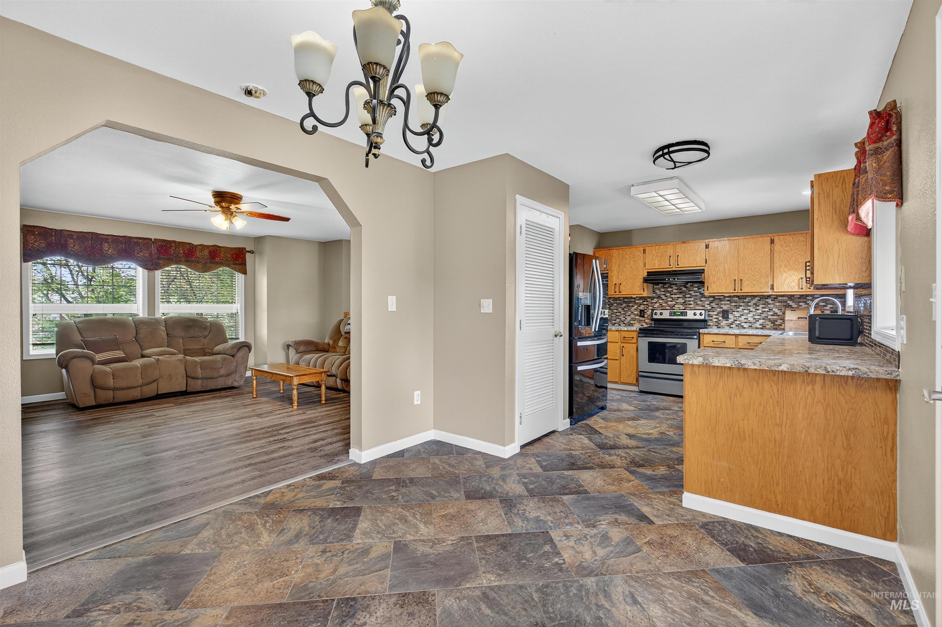 Kitchen featuring open floor plan, arched walkways, tasteful backsplash, light countertops, and stainless steel range with electric cooktop