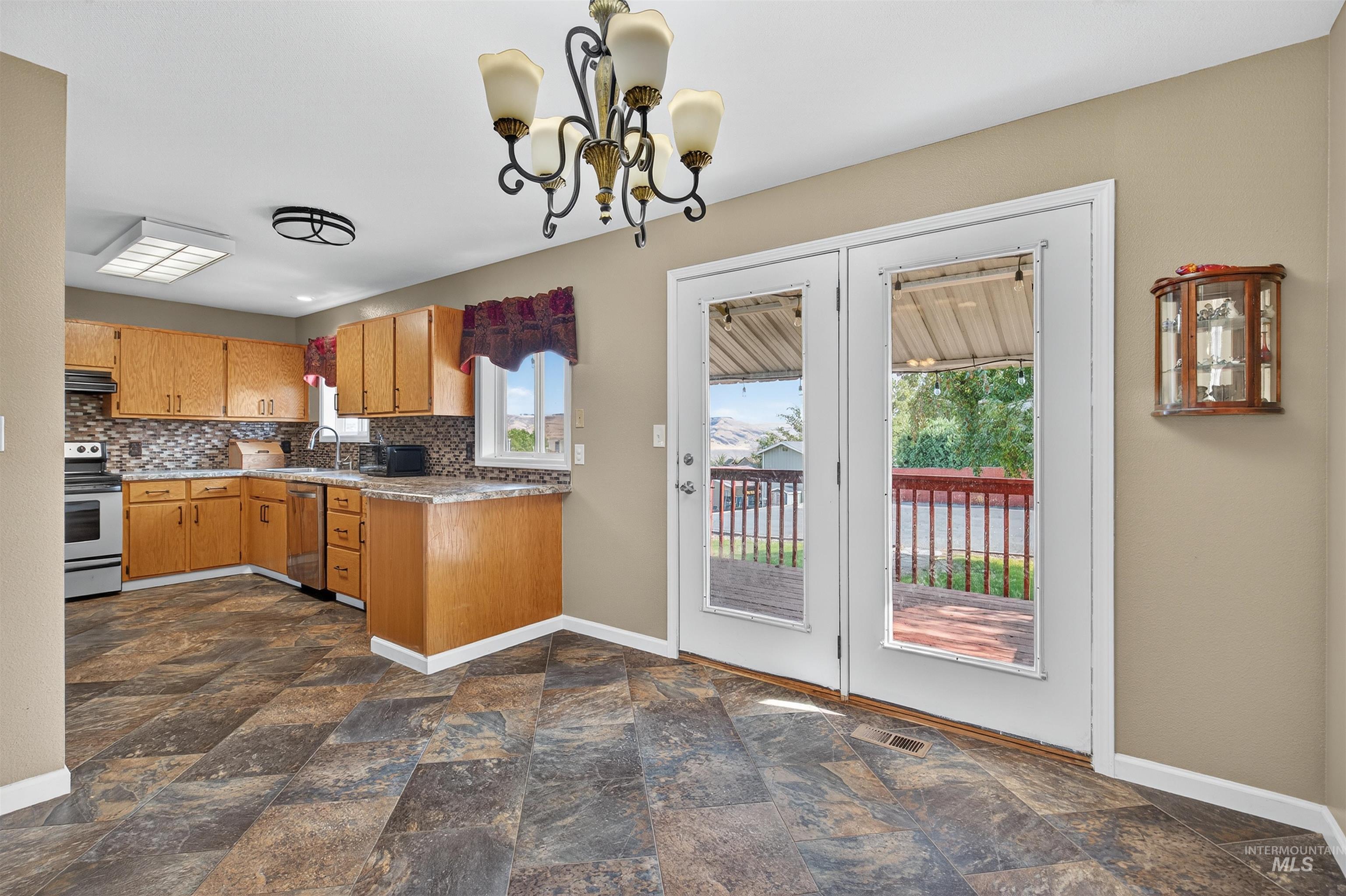 Kitchen featuring a chandelier, healthy amount of natural light, and dark stone finish flooring