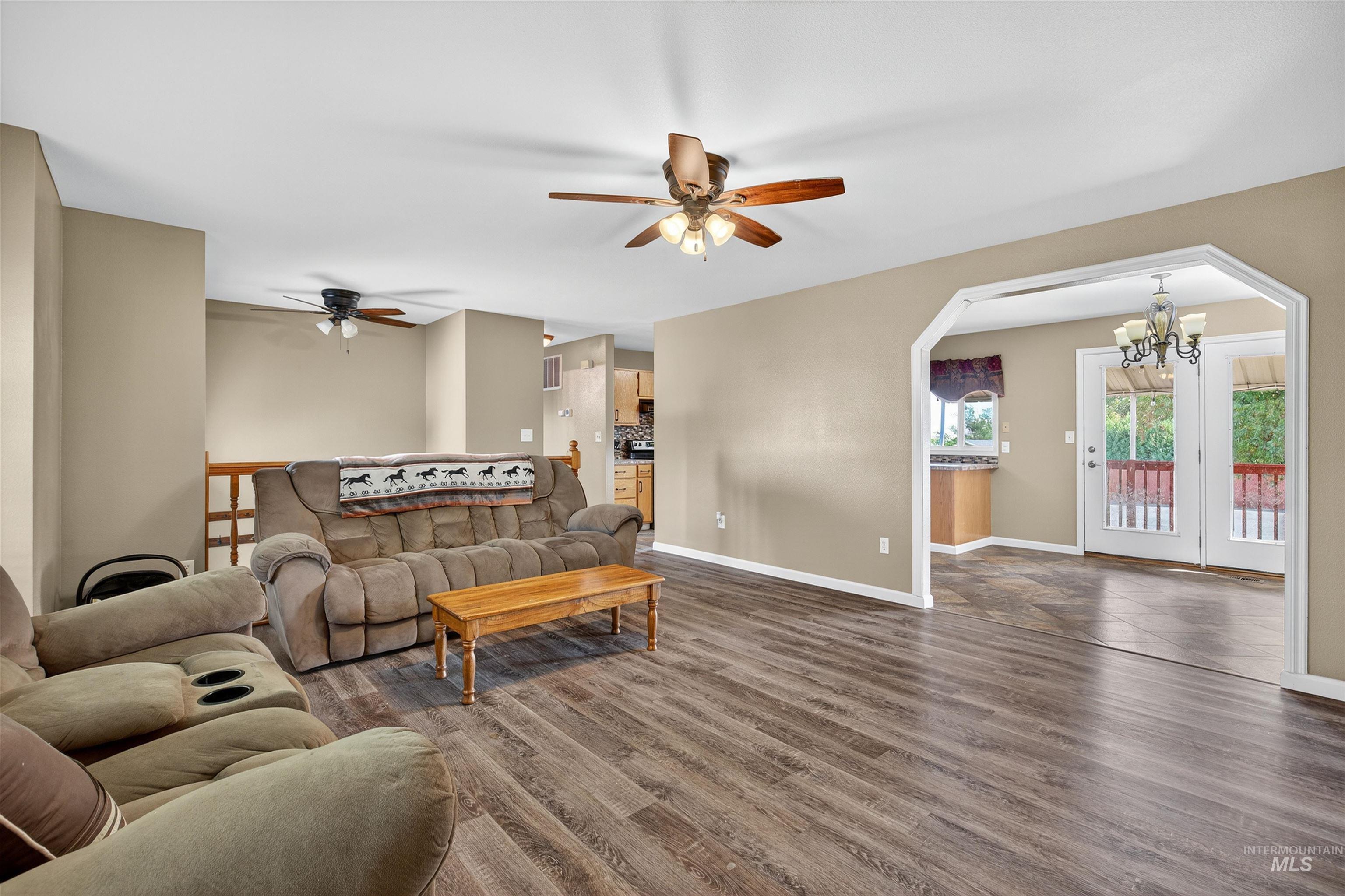 Living room with wood finished floors, a chandelier, and arched walkways