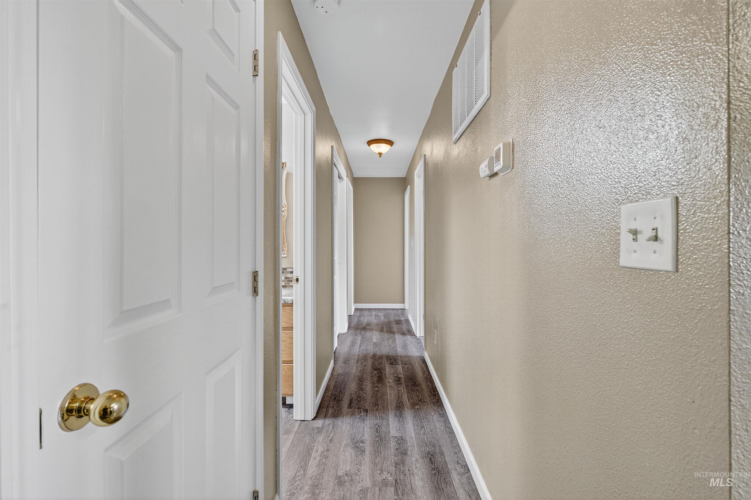 Corridor with a textured wall and dark wood-style flooring