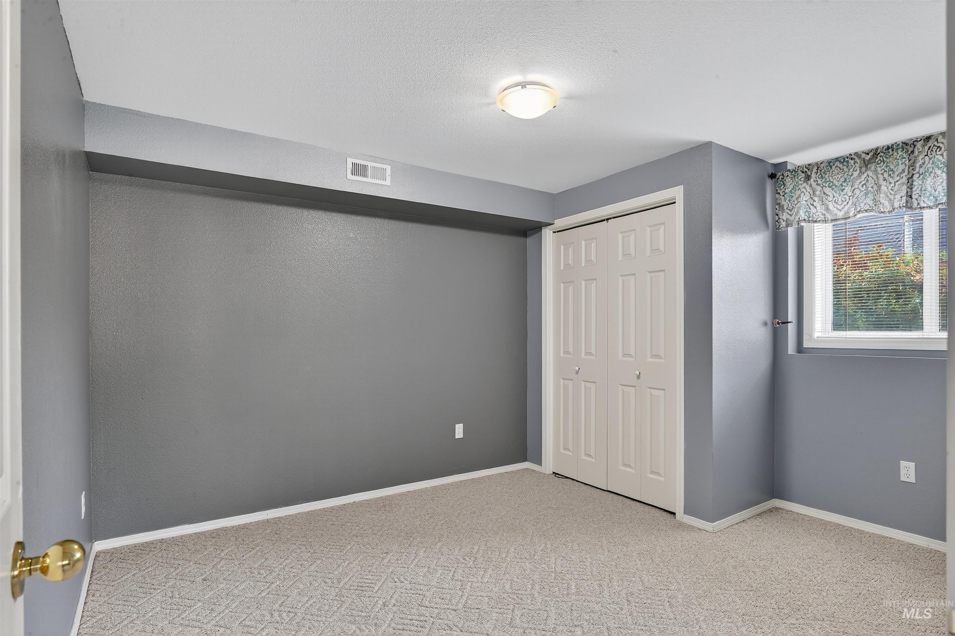 Unfurnished bedroom with light carpet, a closet, and a textured ceiling