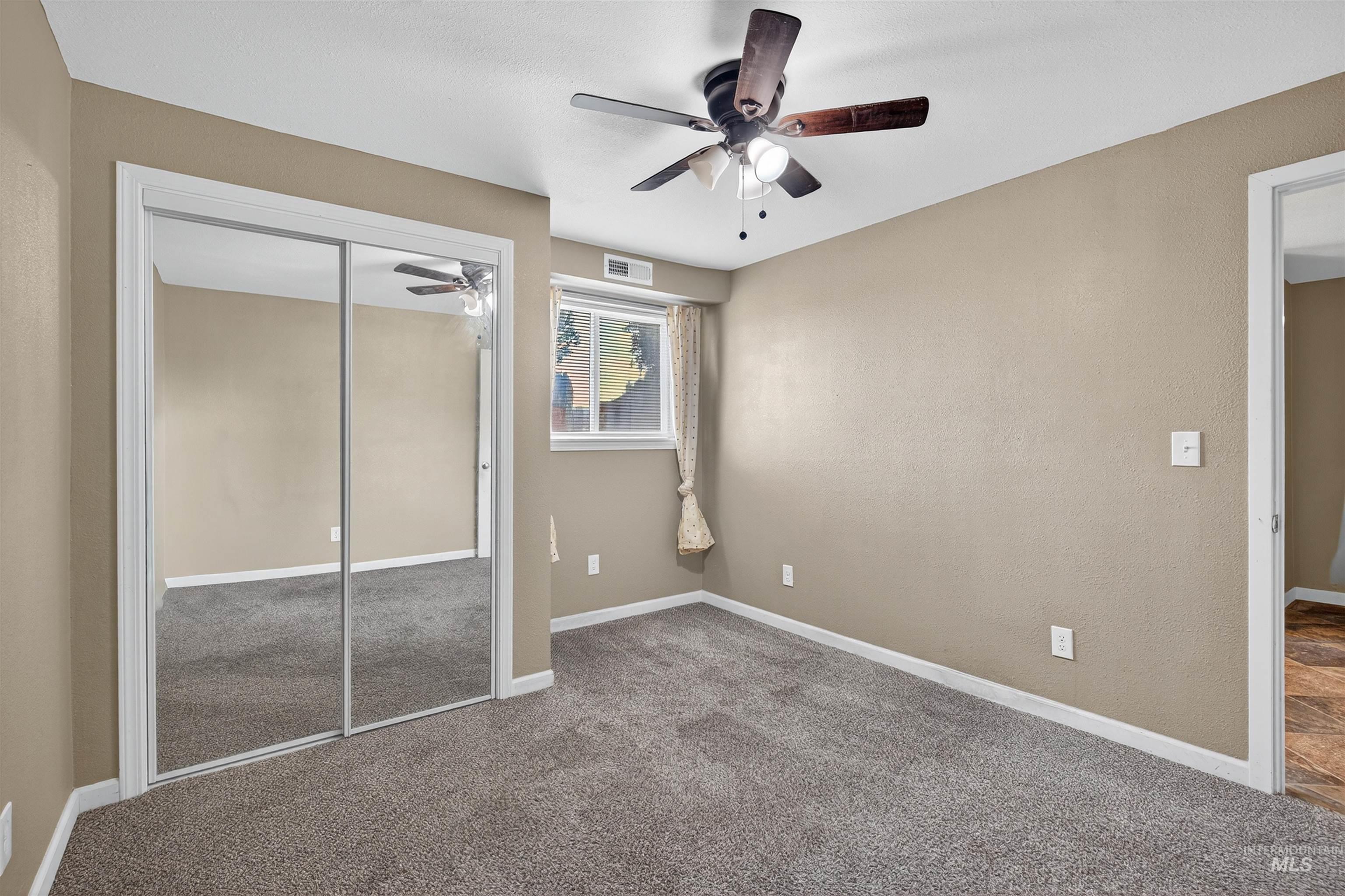 Unfurnished bedroom featuring carpet, a closet, and a ceiling fan
