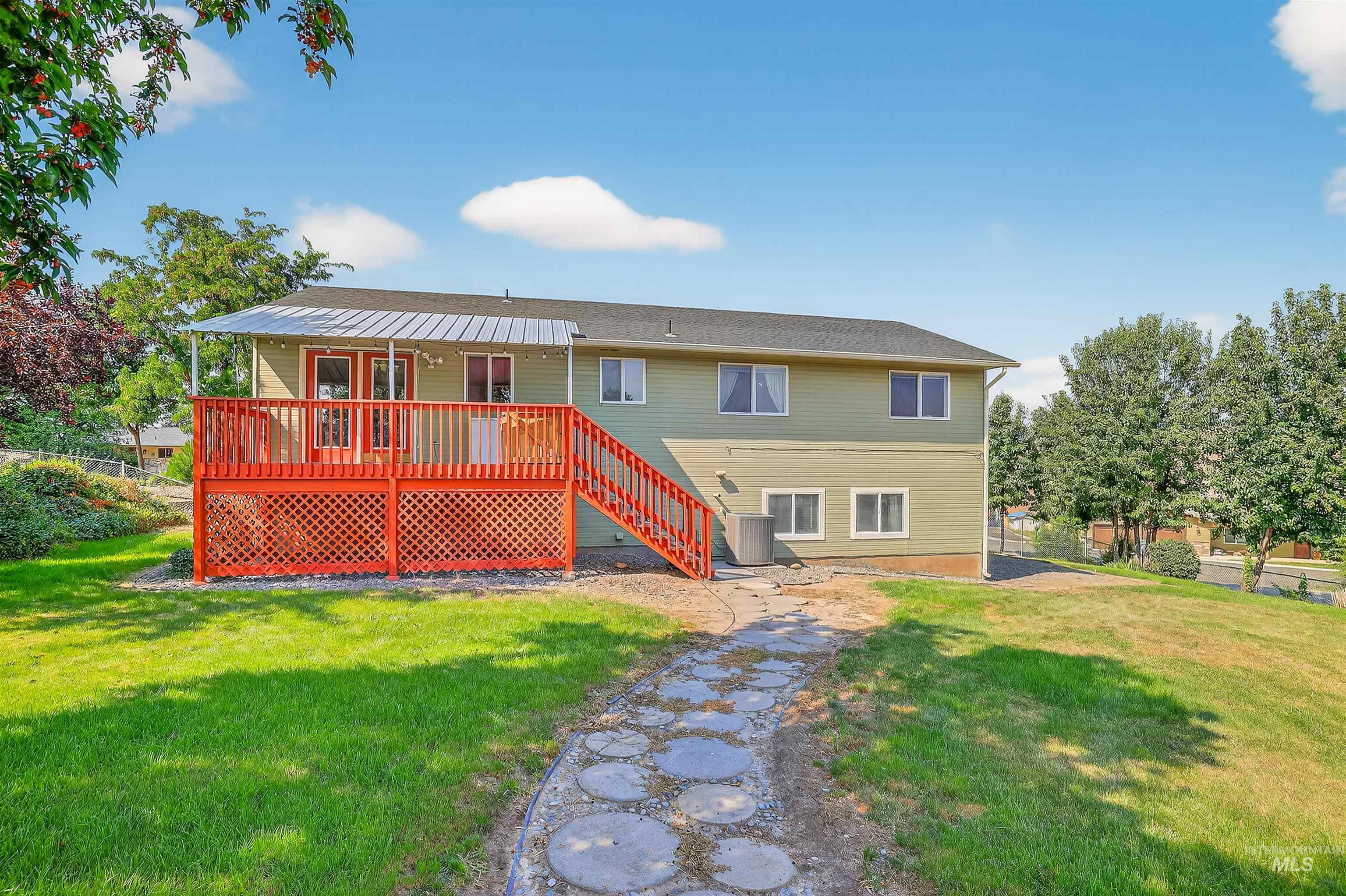 Rear view of house with a lawn, a wooden deck, and stairway