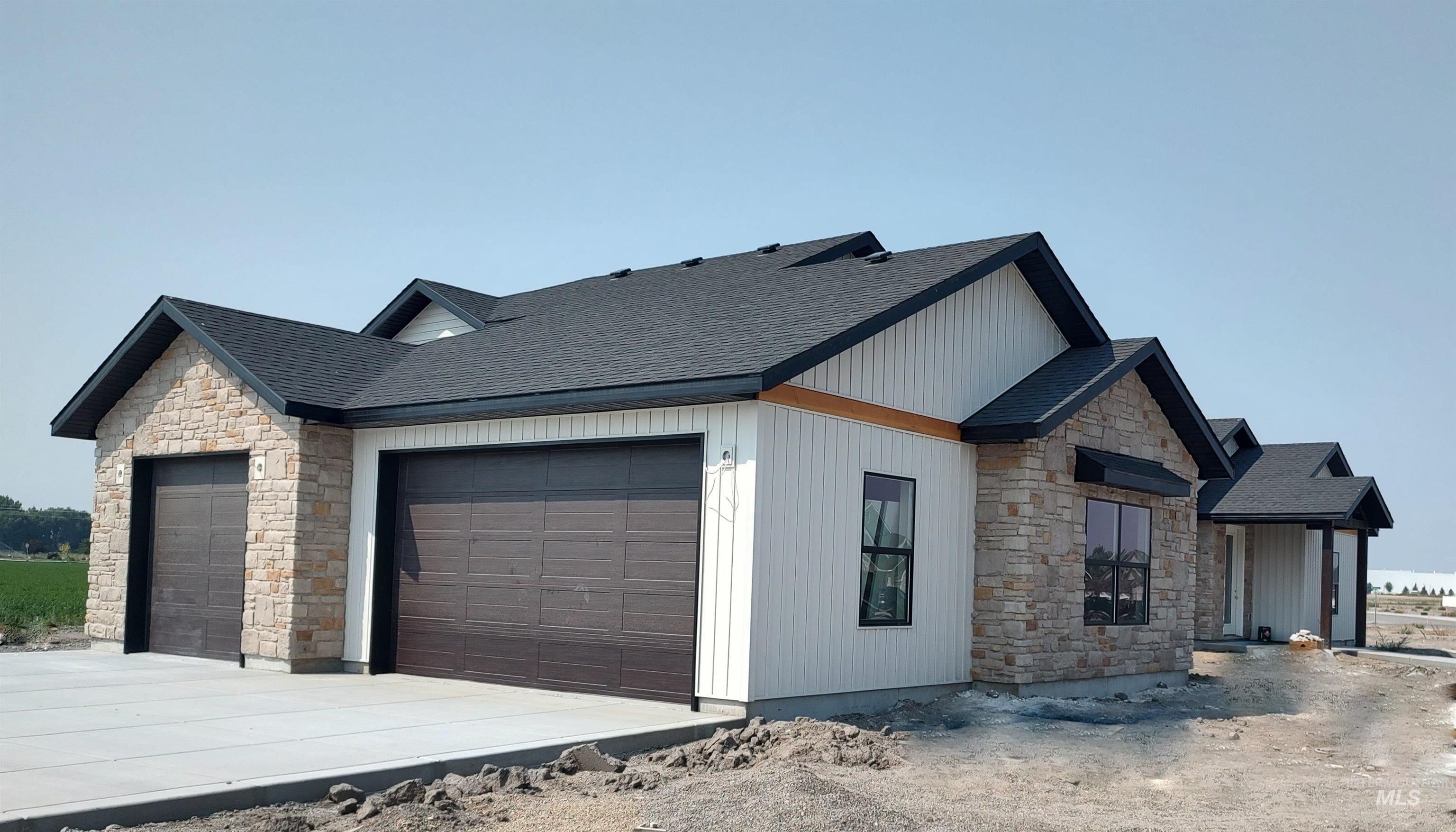 View of property exterior featuring stone siding, an attached garage, a shingled roof, and concrete driveway