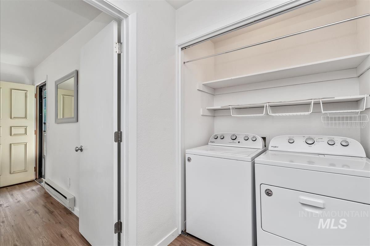 Washroom featuring light wood finished floors, a baseboard radiator, and separate washer and dryer