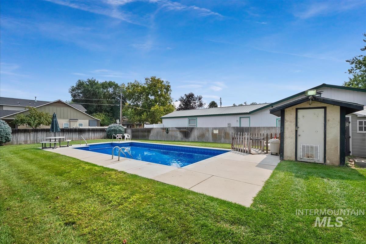 View of swimming pool featuring a fenced backyard, a storage shed, and a patio