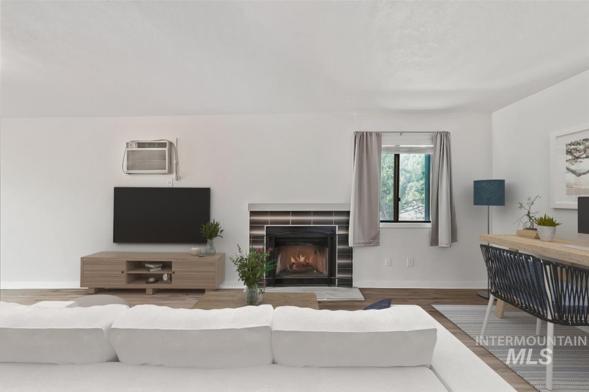 Living area featuring wood finished floors, a fireplace, and a wall mounted air conditioner