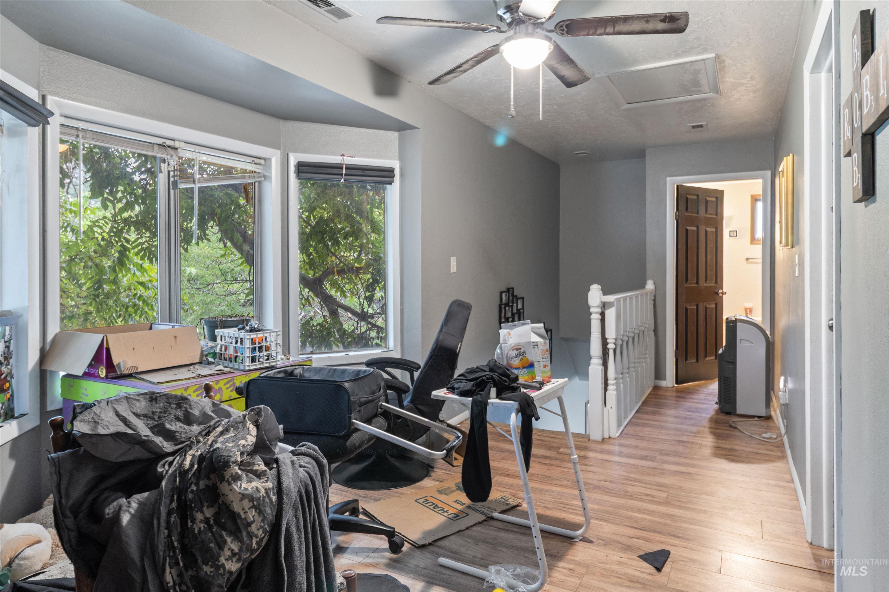Exercise area featuring light wood-style flooring, attic access, and a ceiling fan