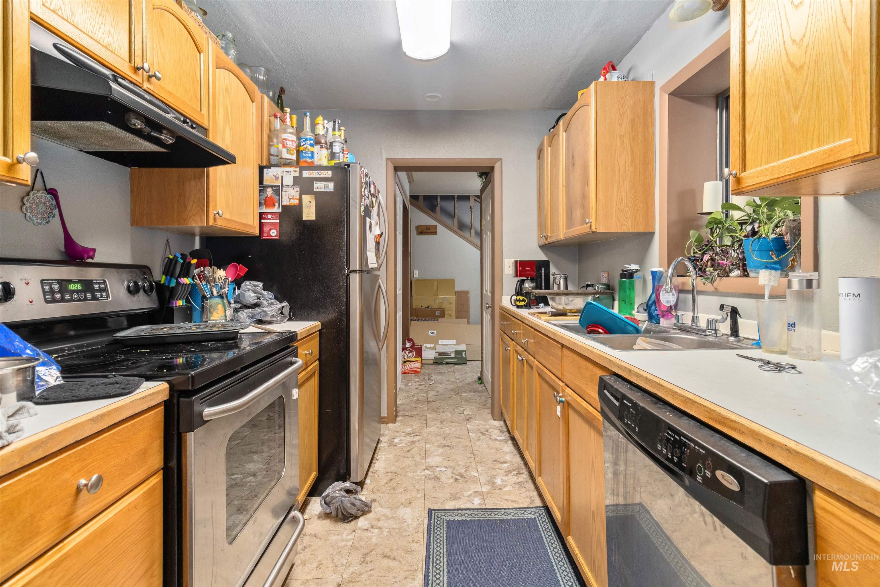 Kitchen with stainless steel appliances, under cabinet range hood, and light countertops