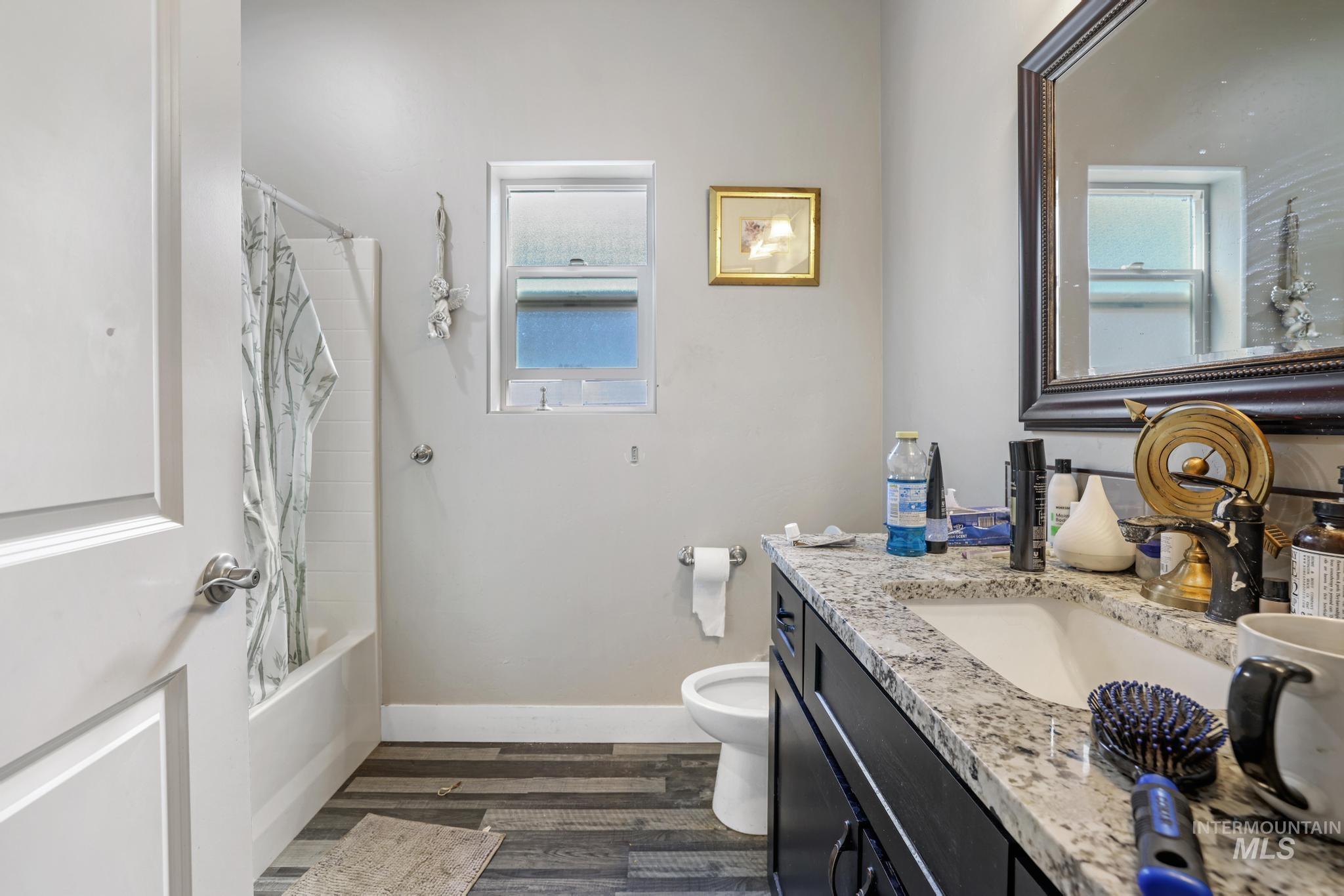 Bathroom featuring shower / tub combo with curtain, vanity, dark wood-style flooring, and healthy amount of natural light