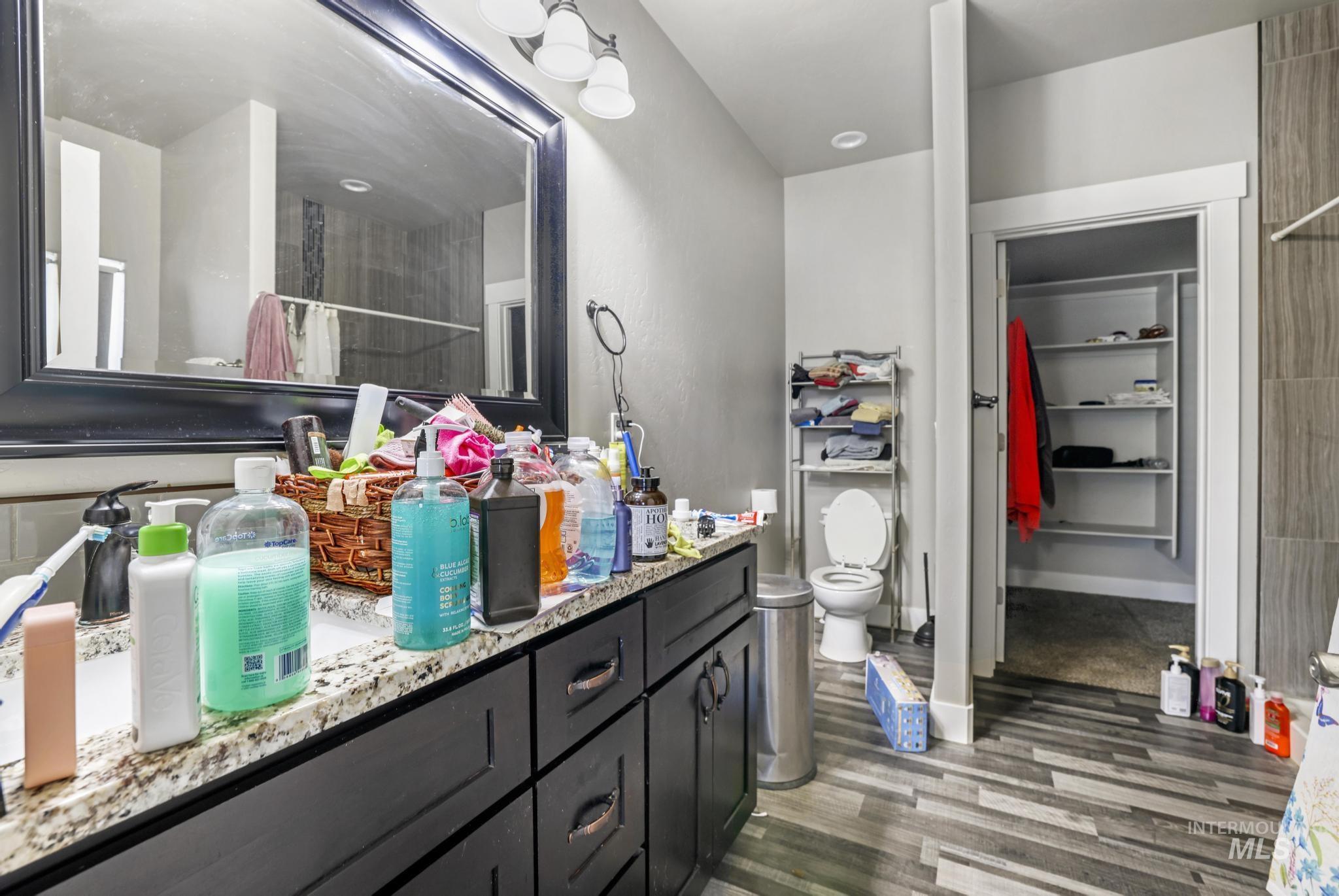 Bathroom with dark wood-style flooring, a tile shower, and vanity