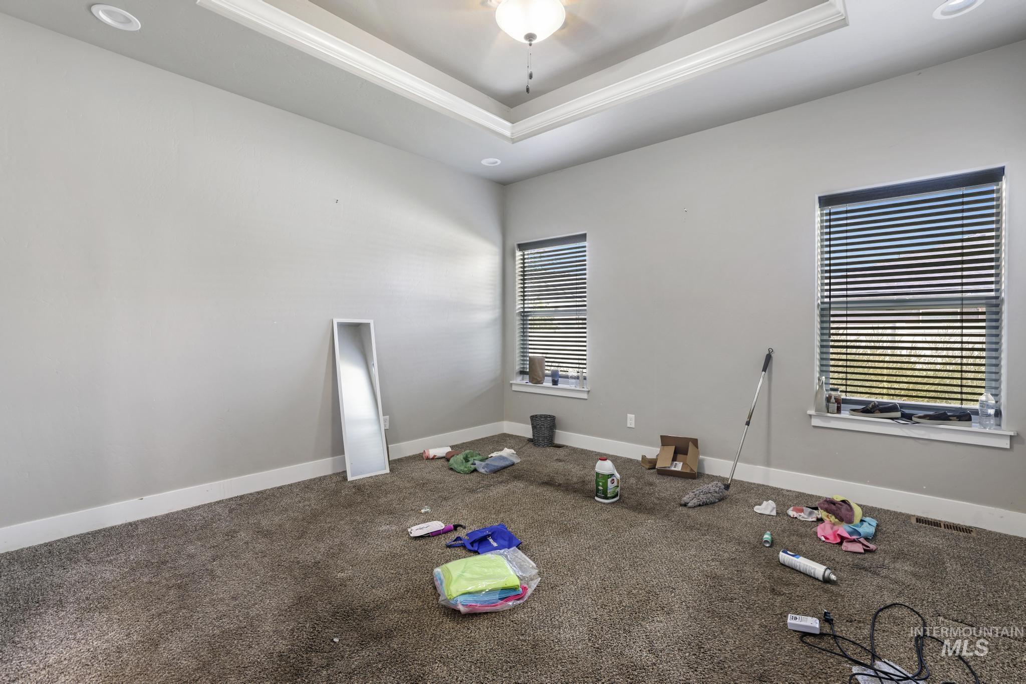 Carpeted empty room featuring a tray ceiling and ceiling fan