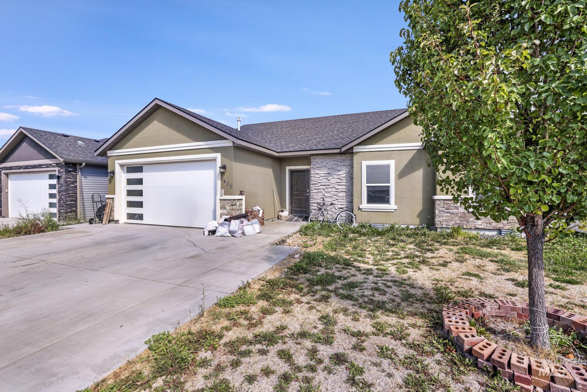 Ranch-style house featuring stone siding, stucco siding, a shingled roof, and an attached garage