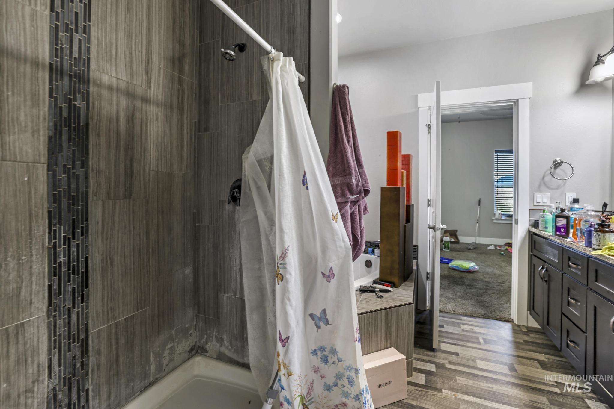 Full bathroom with a shower stall, dark wood-style floors, and vanity