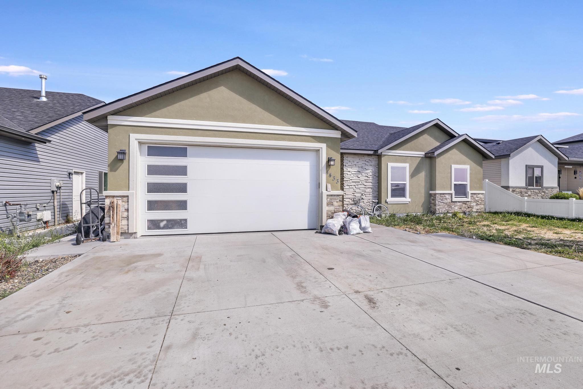 View of front of house featuring stucco siding, stone siding, driveway, and an attached garage