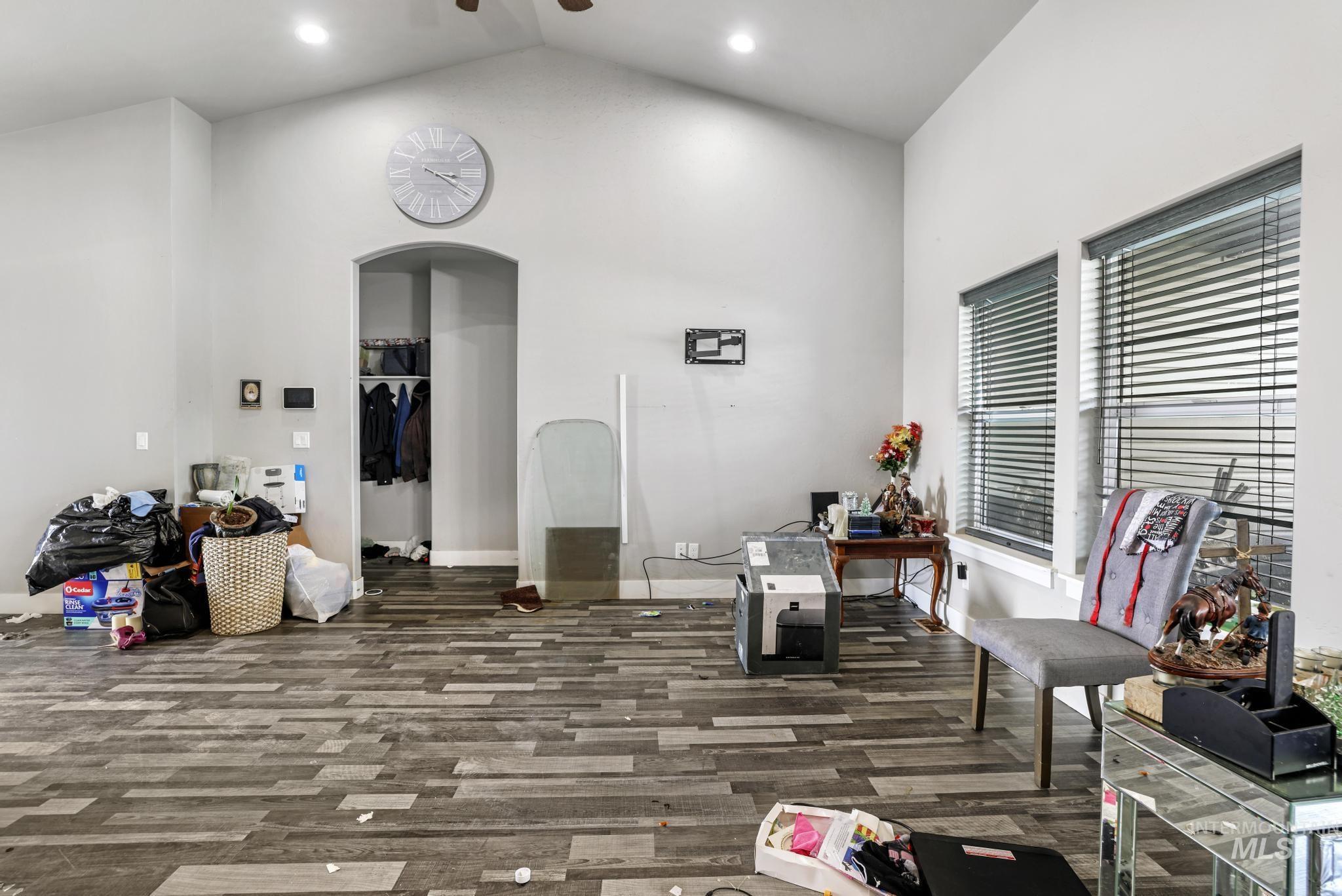 Home office with arched walkways, high vaulted ceiling, wood finished floors, and recessed lighting