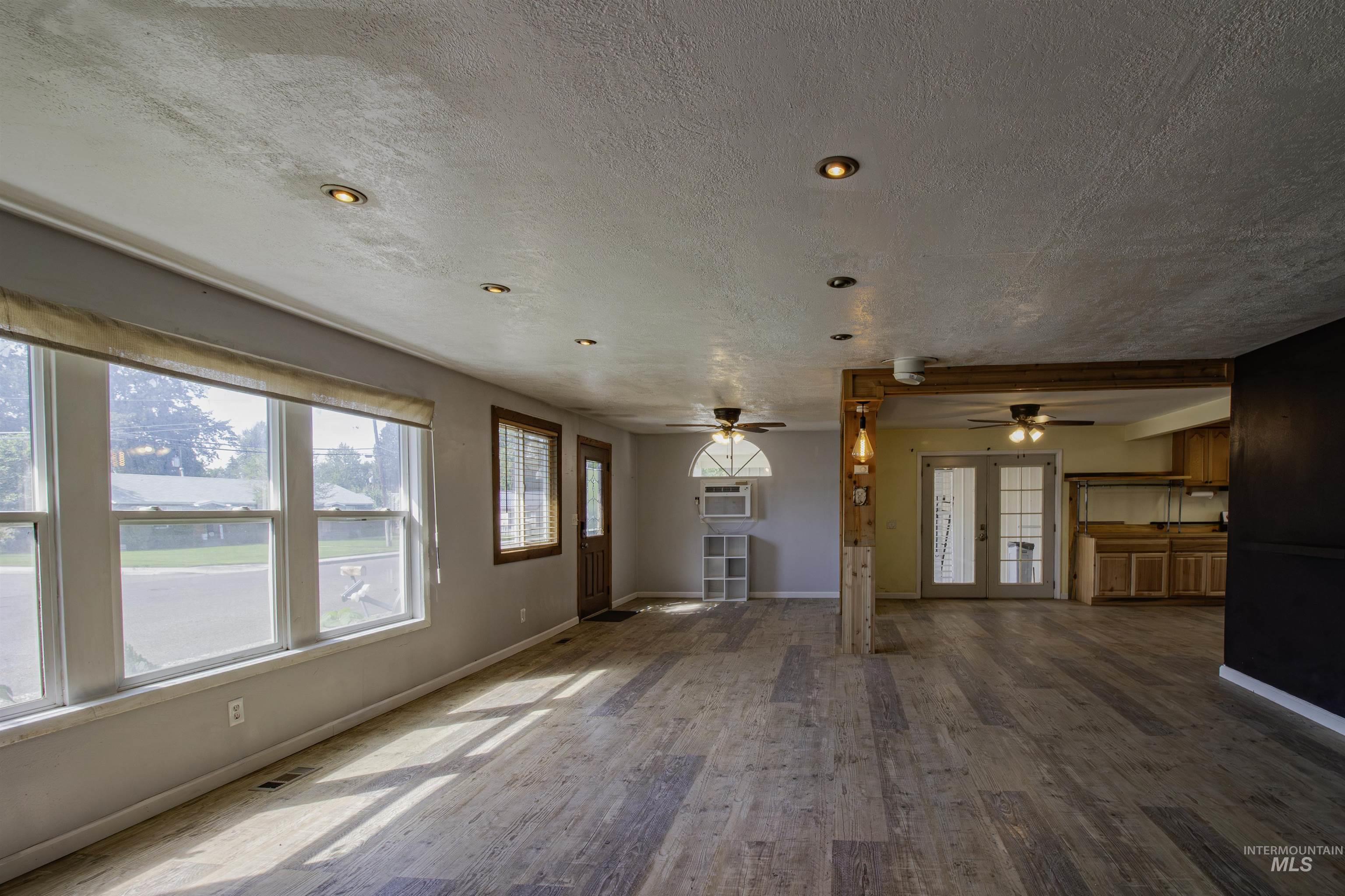 Unfurnished living room with wood finished floors, plenty of natural light, a textured ceiling, and french doors