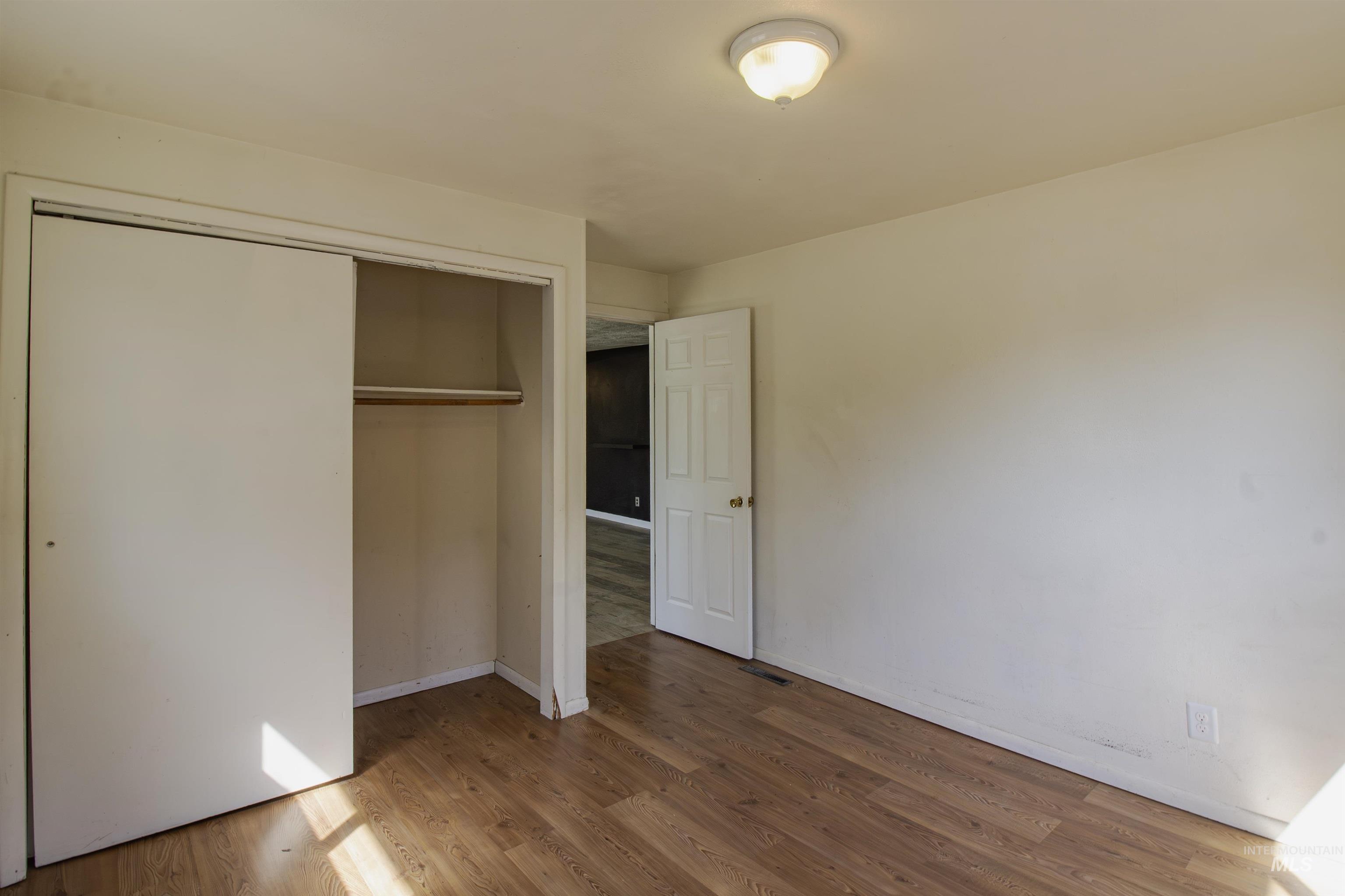 Unfurnished bedroom with wood finished floors and a closet