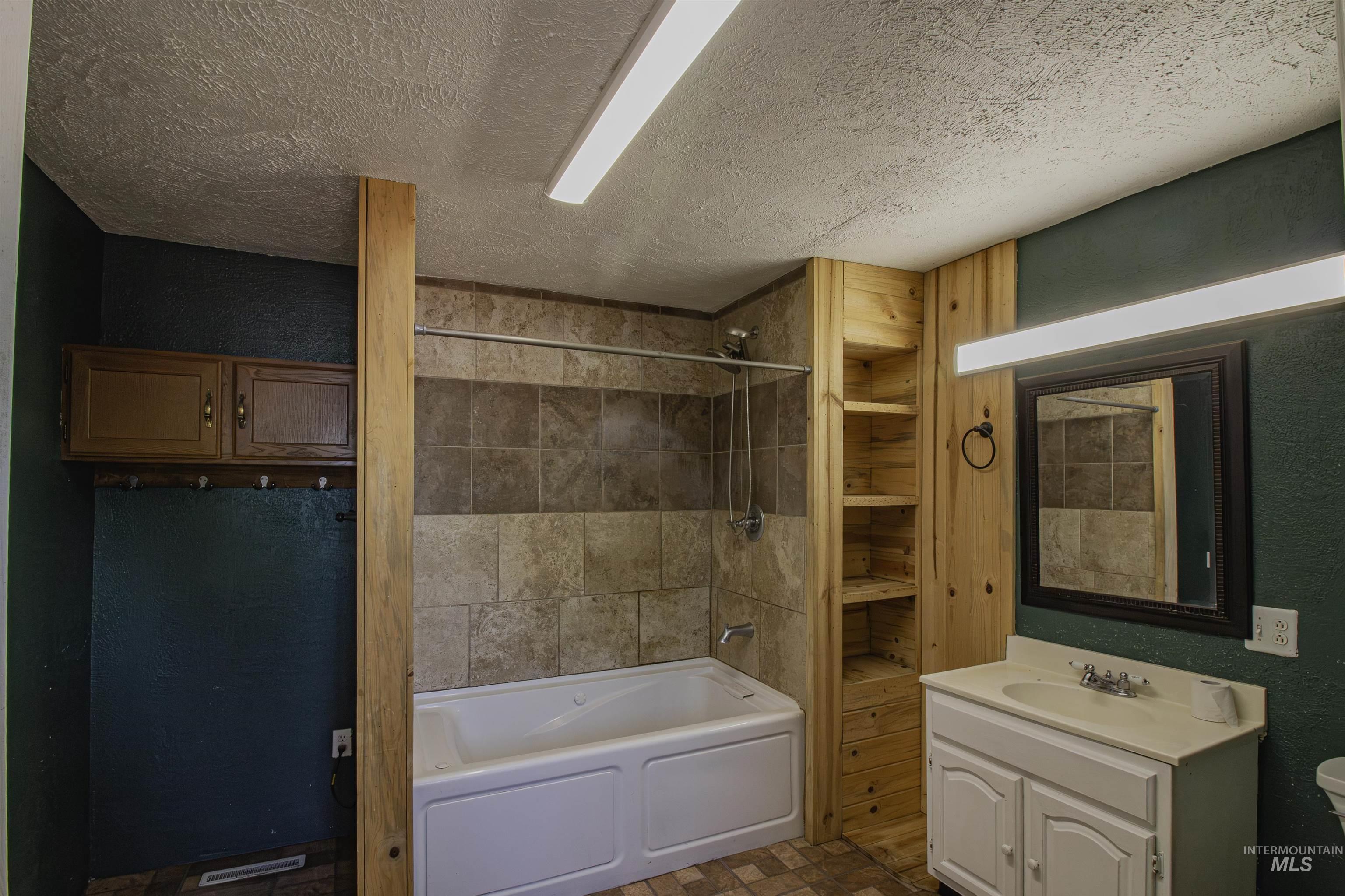 Full bath featuring shower / washtub combination, a textured wall, vanity, and a textured ceiling