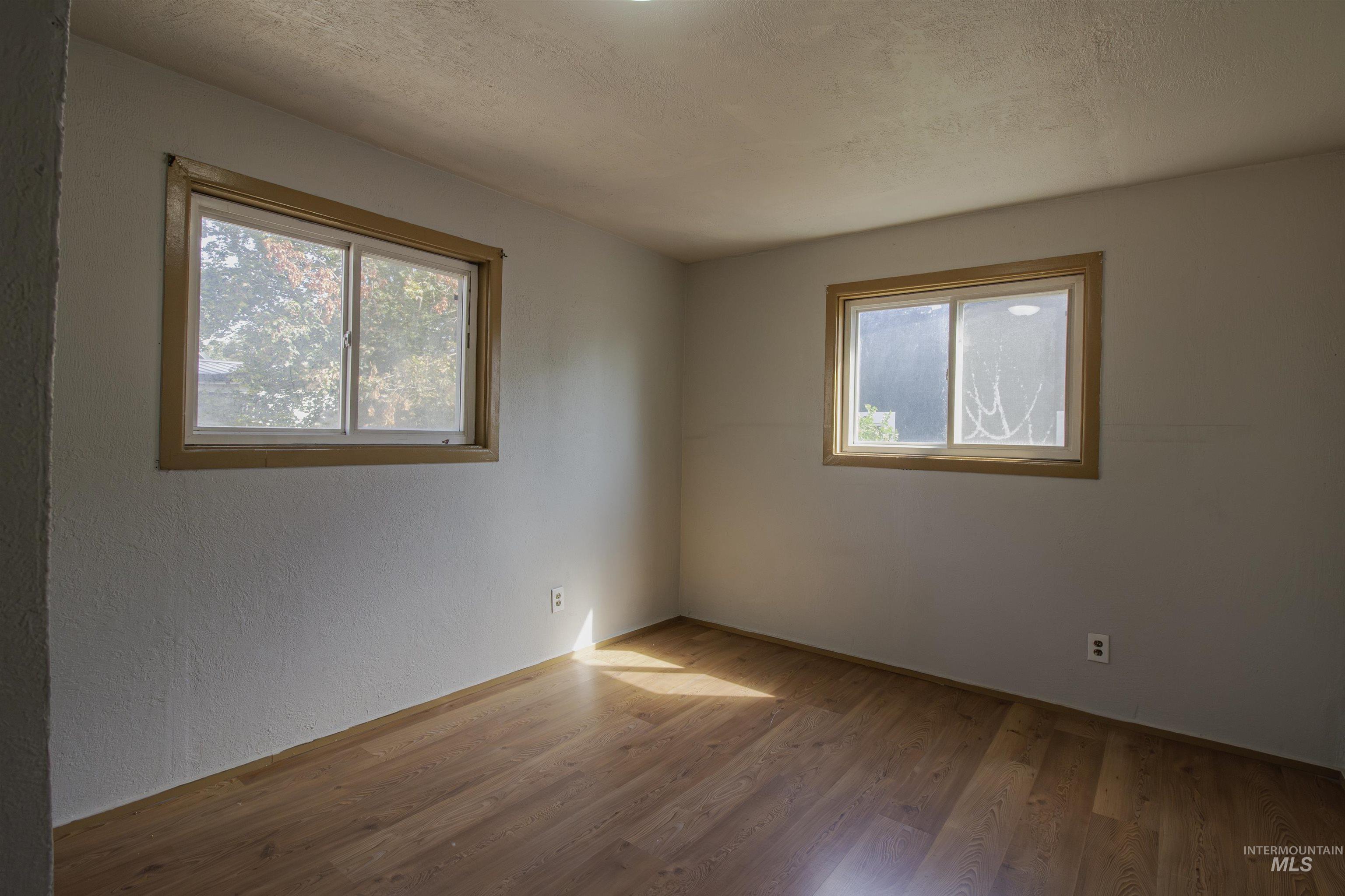 Spare room with wood finished floors and a textured ceiling
