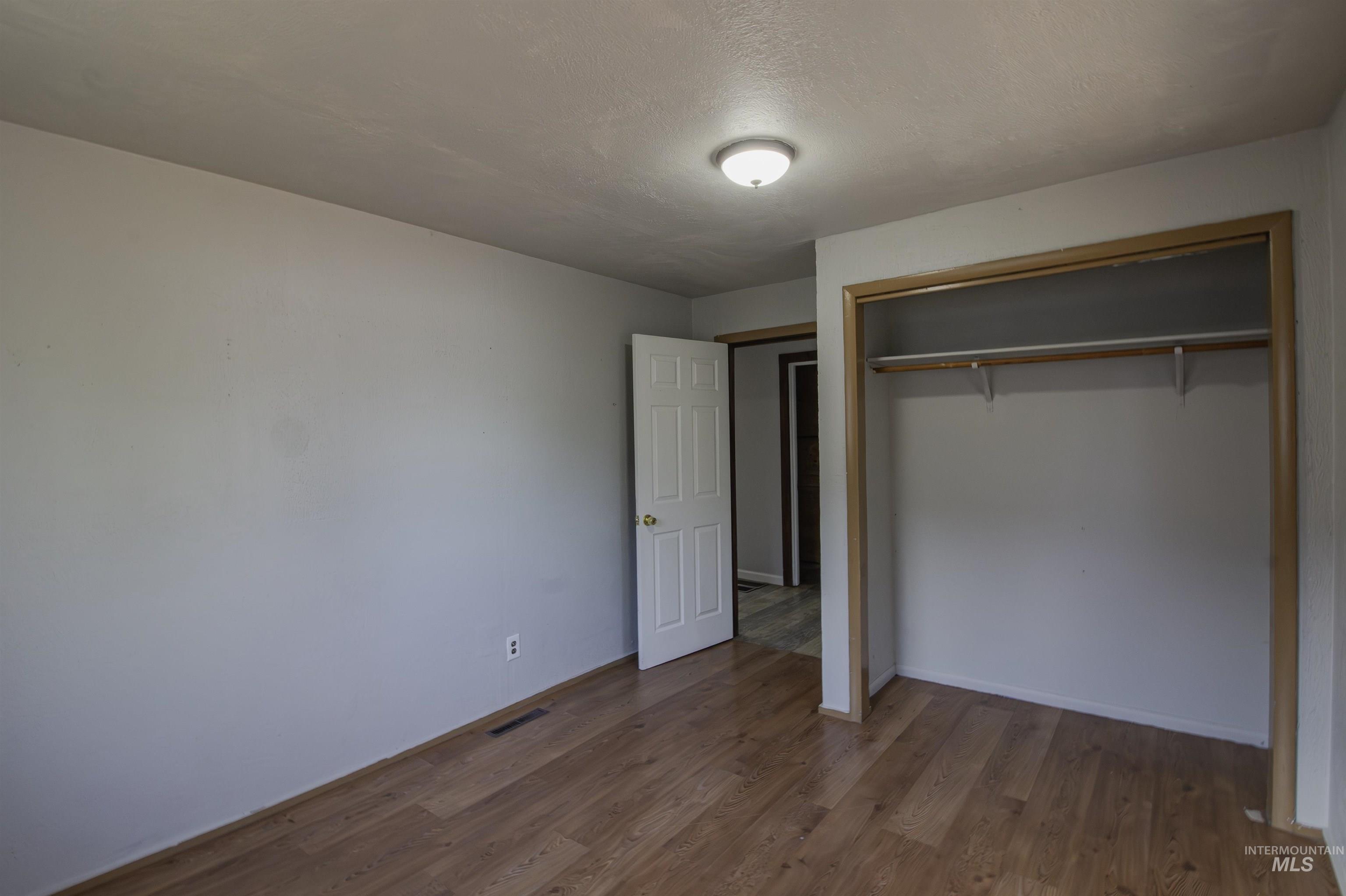Unfurnished bedroom featuring dark wood-style floors, a closet, and a textured ceiling