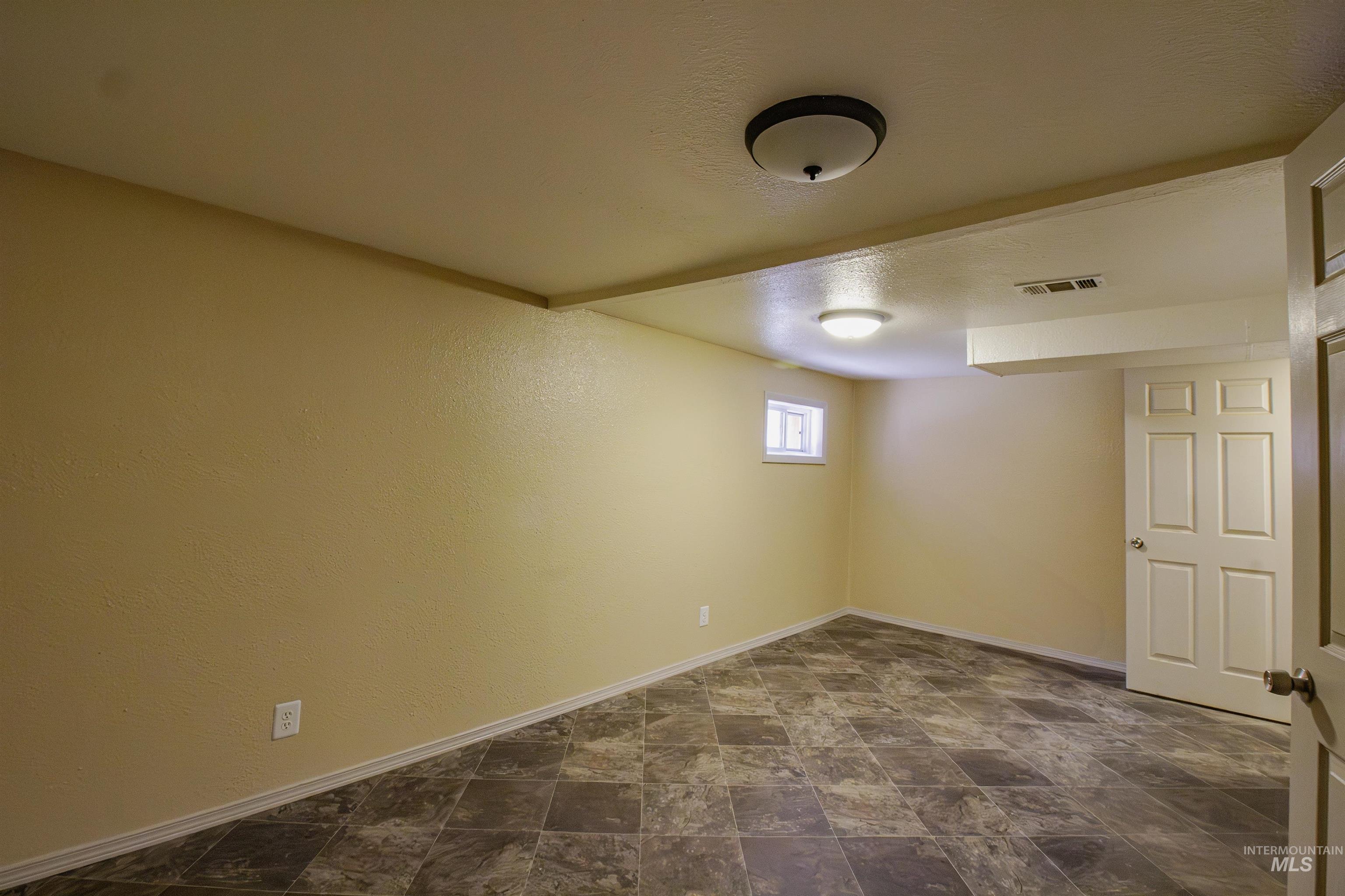 Below grade area featuring stone finish floors, a textured ceiling, and a textured wall
