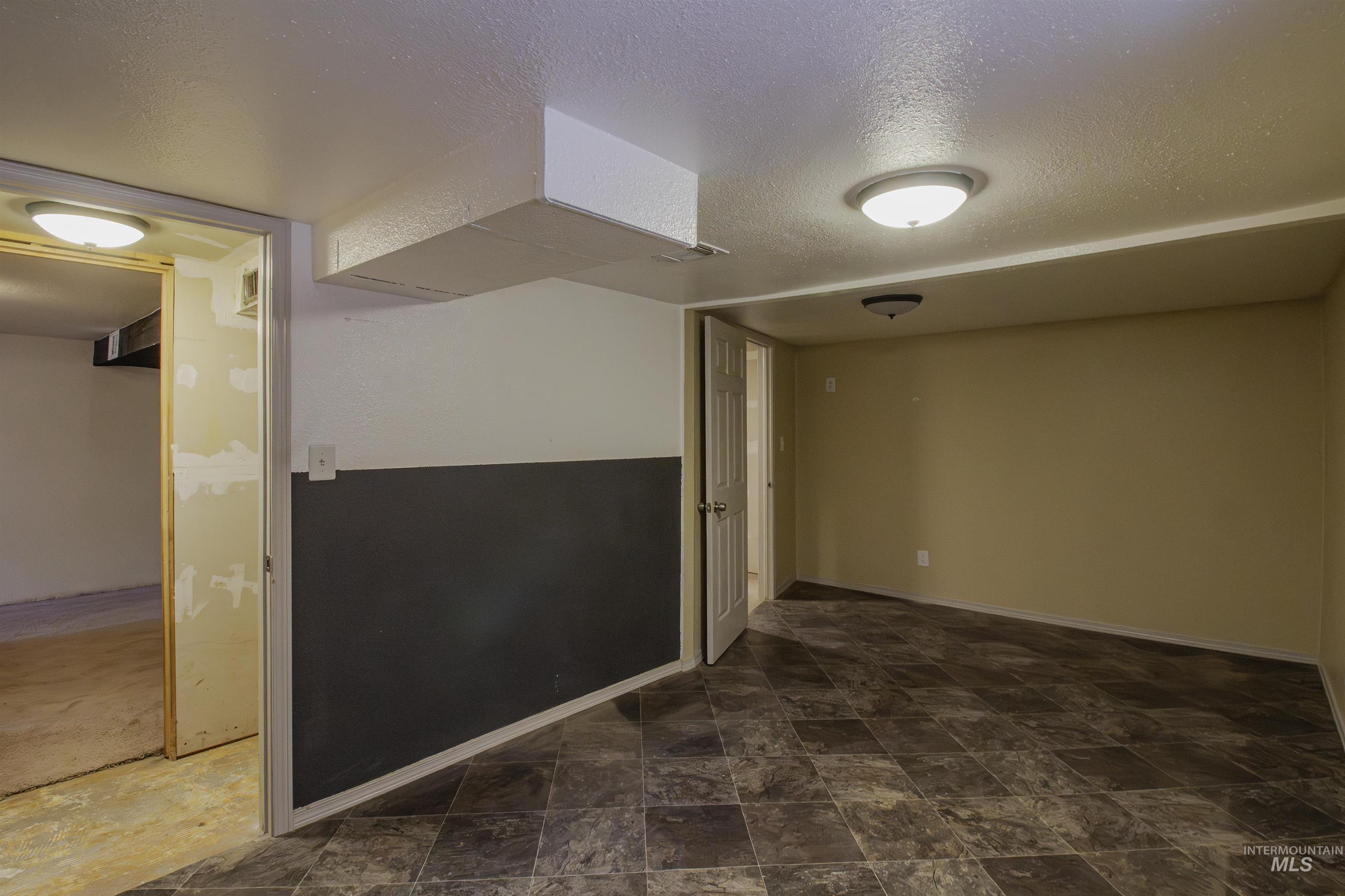 Unfurnished room with a textured ceiling and stone finish floors