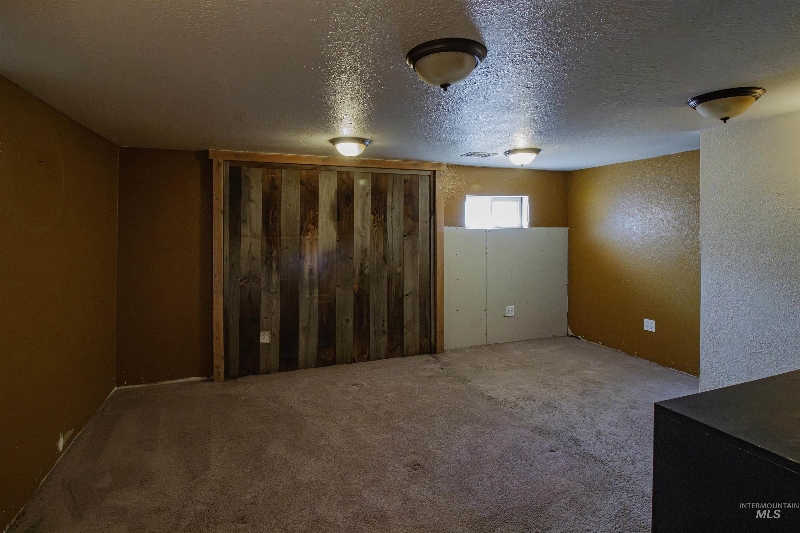 Basement with carpet, a textured ceiling, and a textured wall
