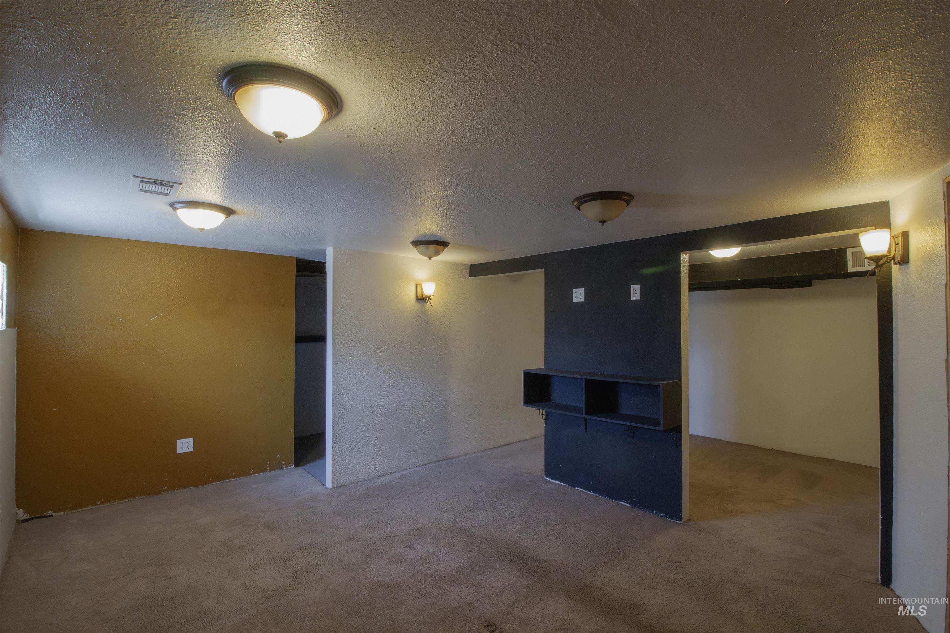 Finished below grade area with a textured ceiling and carpet flooring