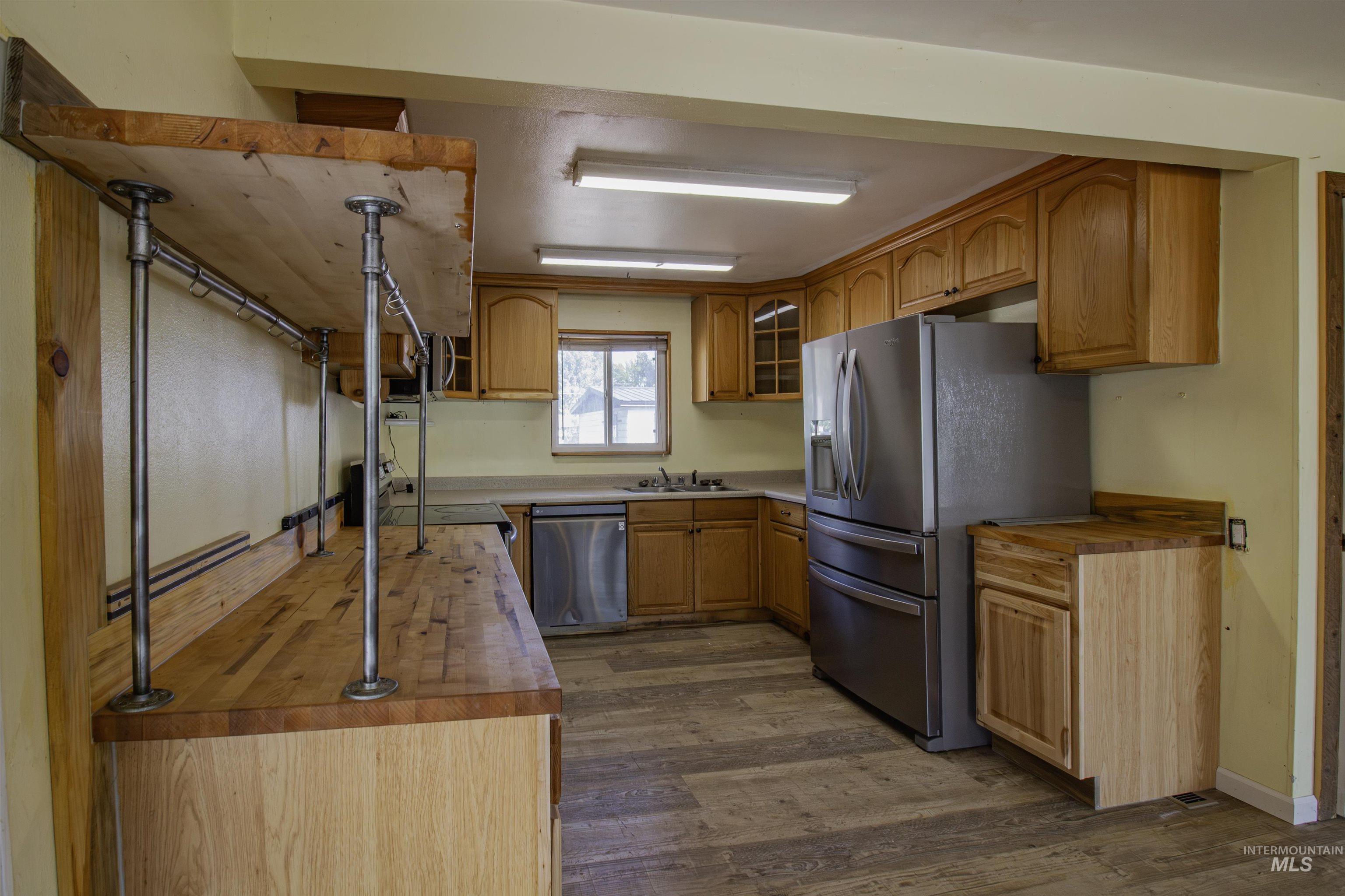 Kitchen featuring butcher block counters, appliances with stainless steel finishes, dark wood finished floors, and glass insert cabinets