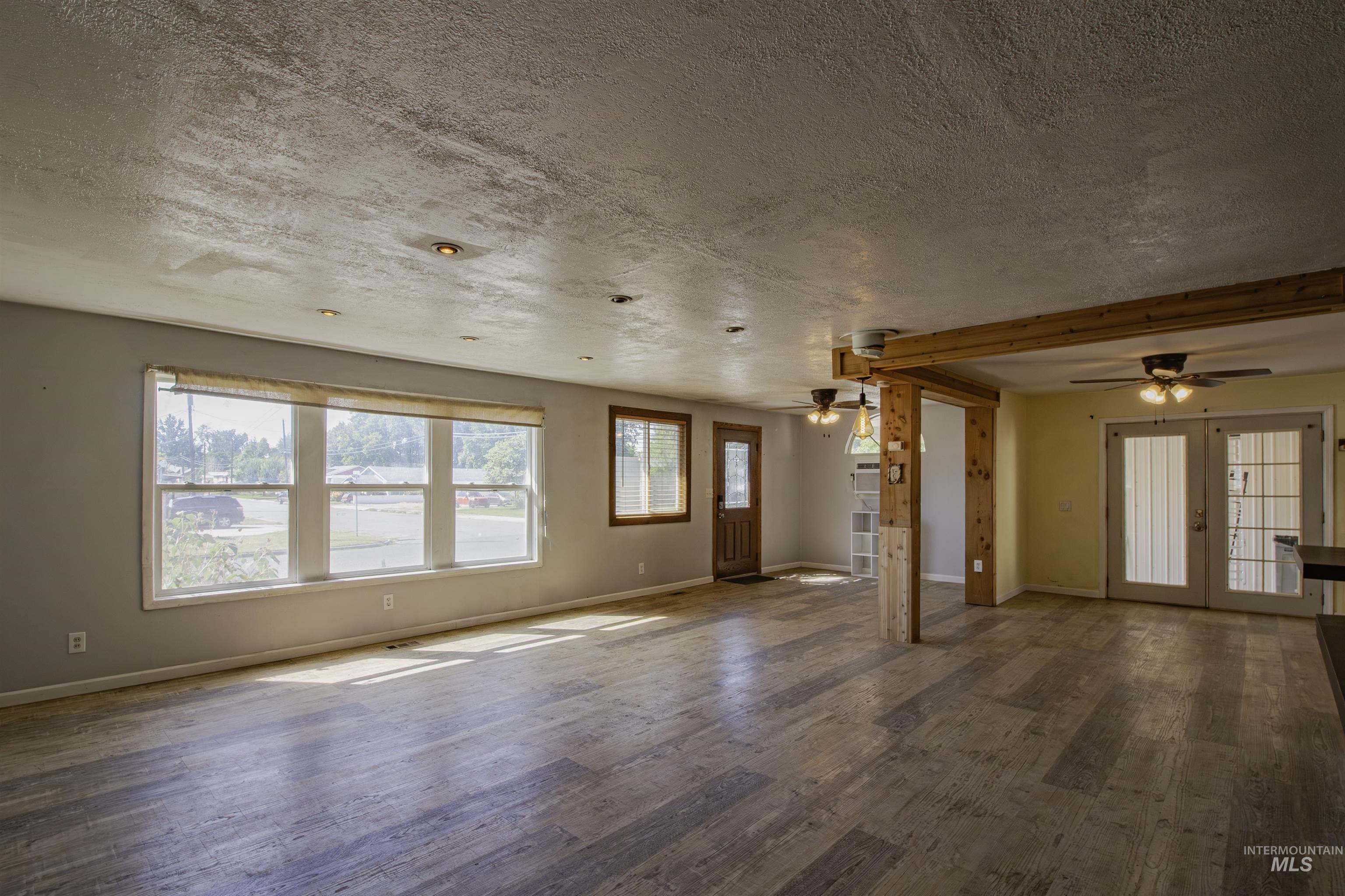 Unfurnished living room featuring wood finished floors, a textured ceiling, french doors, and a ceiling fan