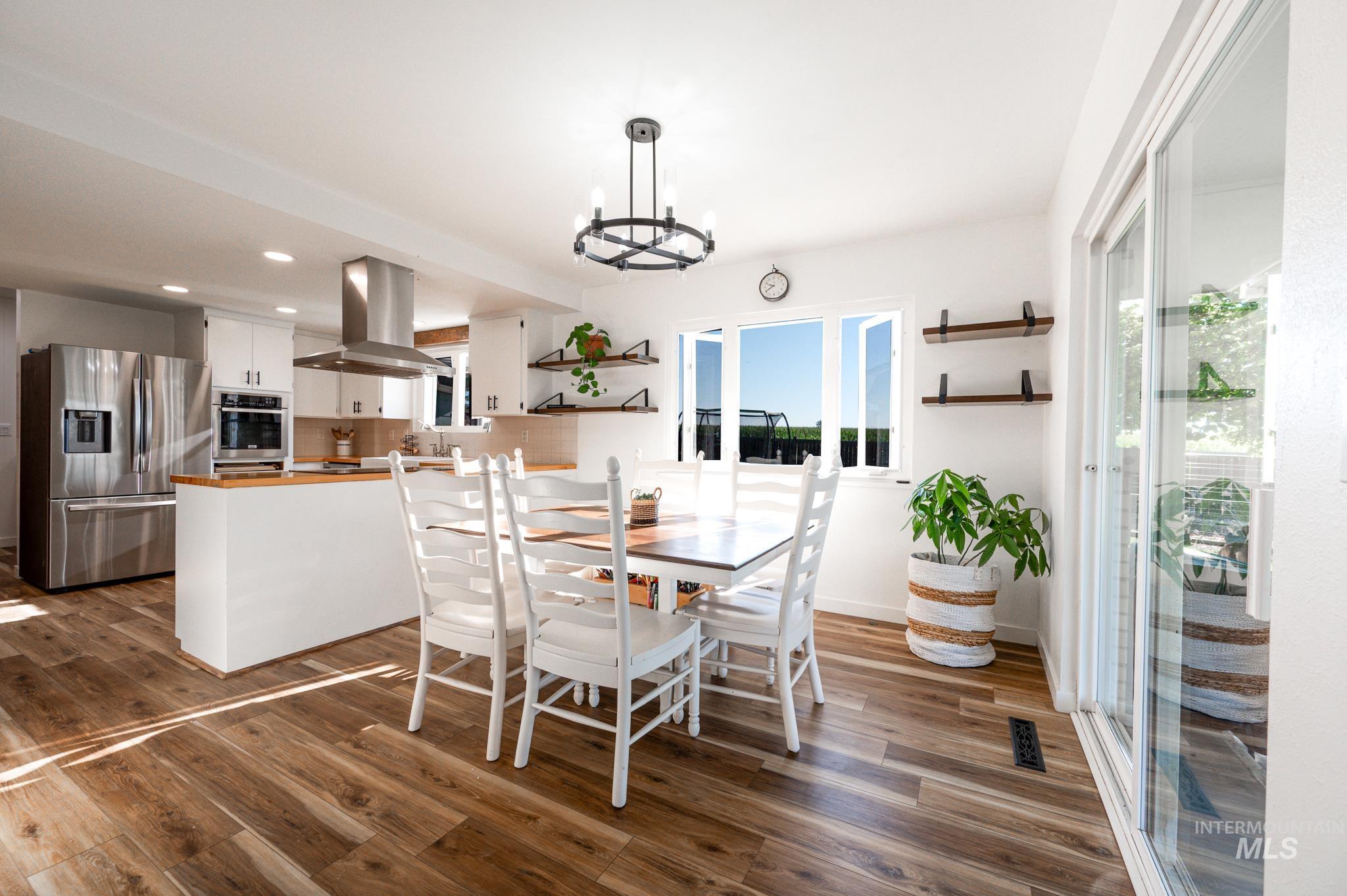 Dining space with dark wood-style flooring, recessed lighting, and a chandelier