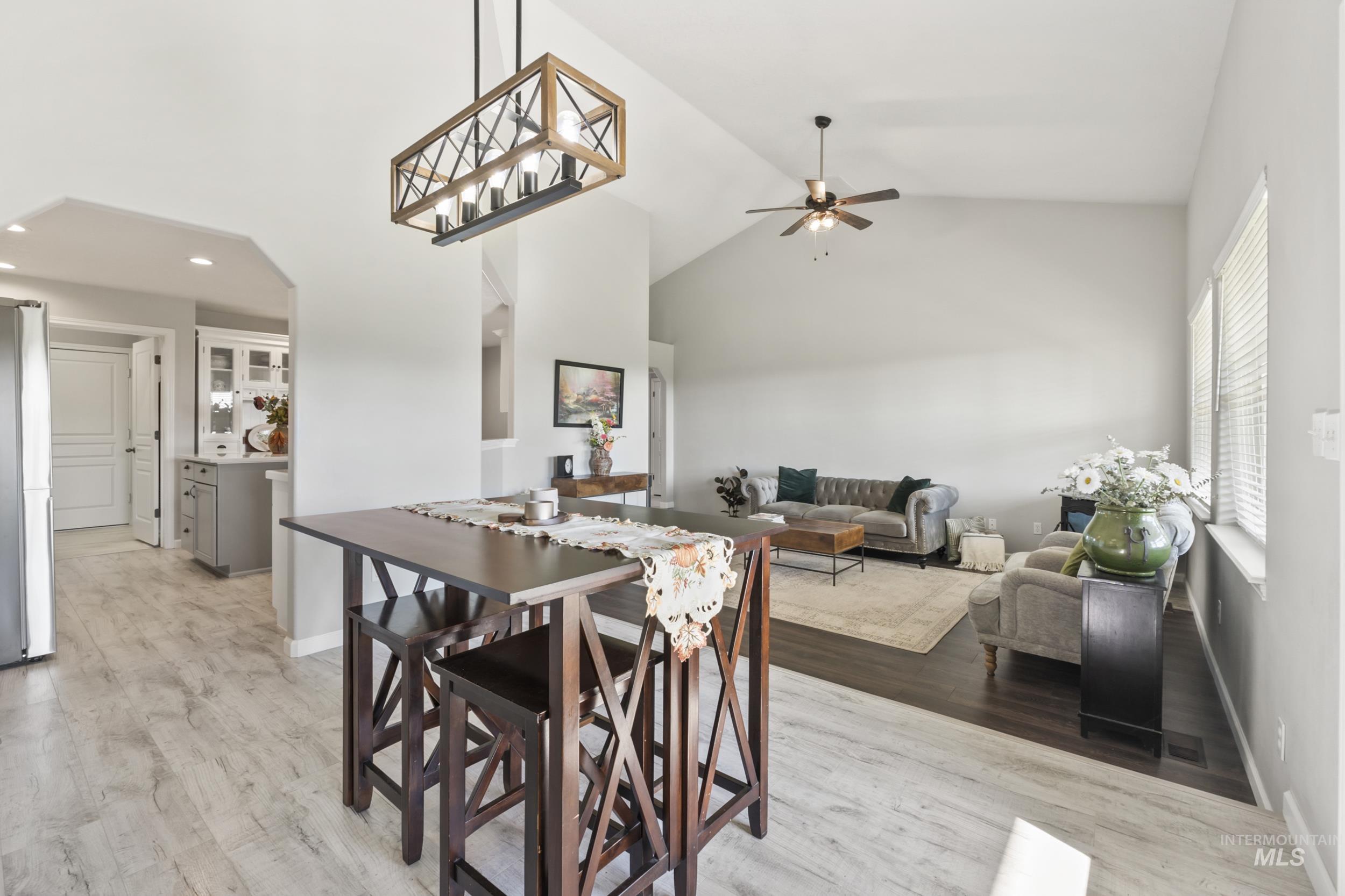 Dining area with high vaulted ceiling, light wood-style flooring, and ceiling fan